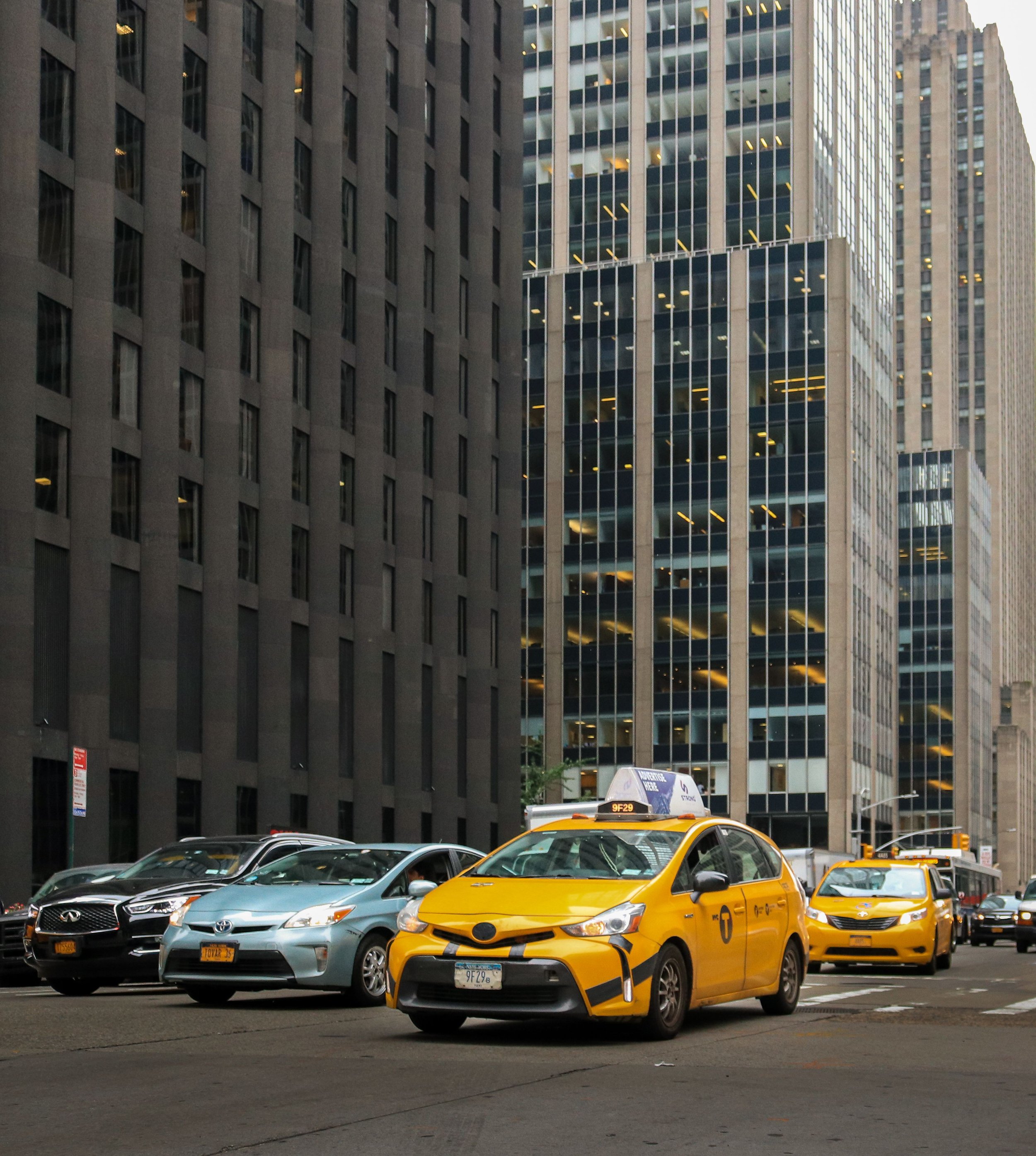 Yellow taxi in busy city traffic, representing New Jersey auto injury claims, with tall buildings on both sides