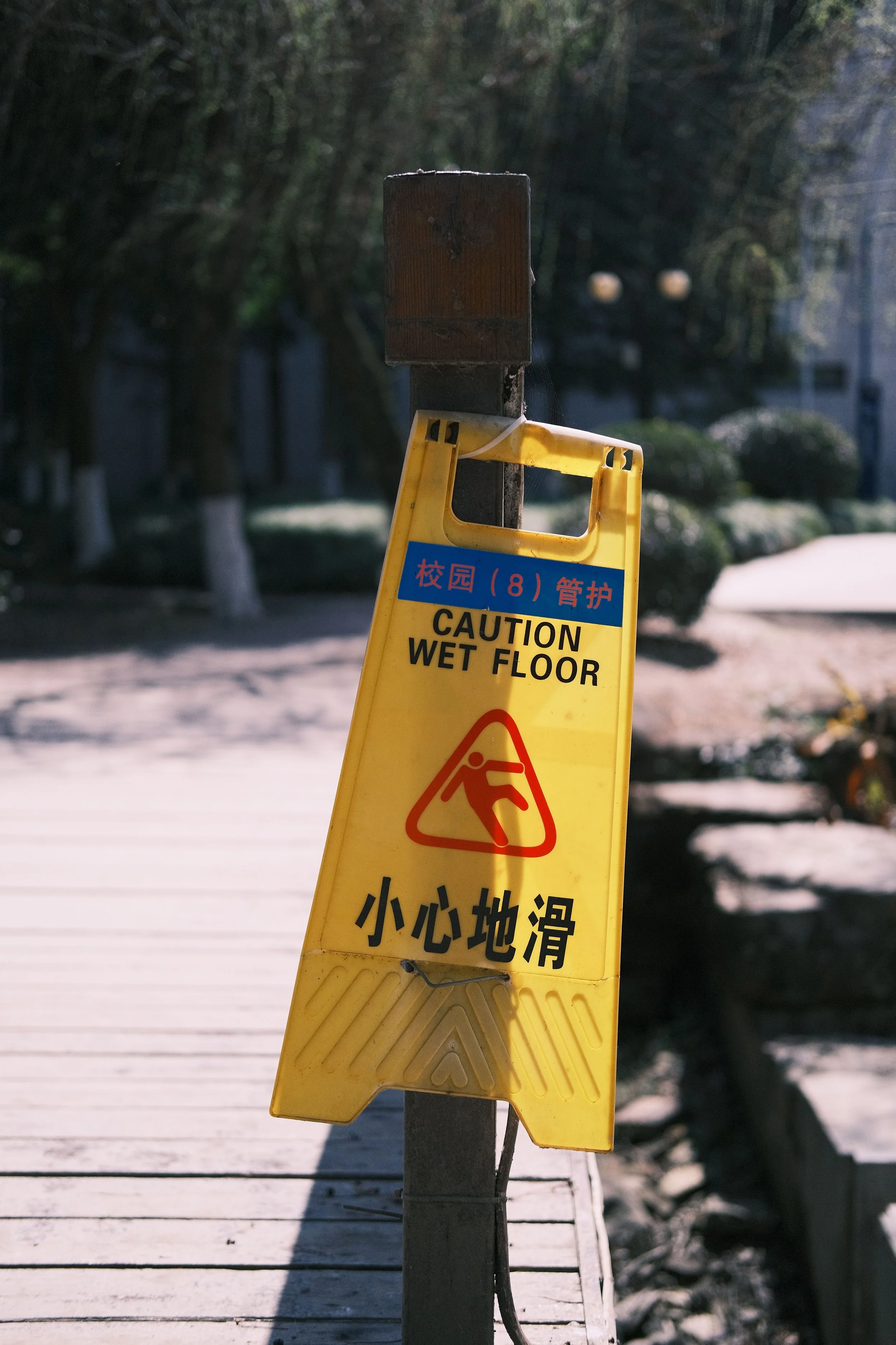 Yellow caution wet floor sign on a pedestrian walkway, representing pedestrian safety and accident hazards