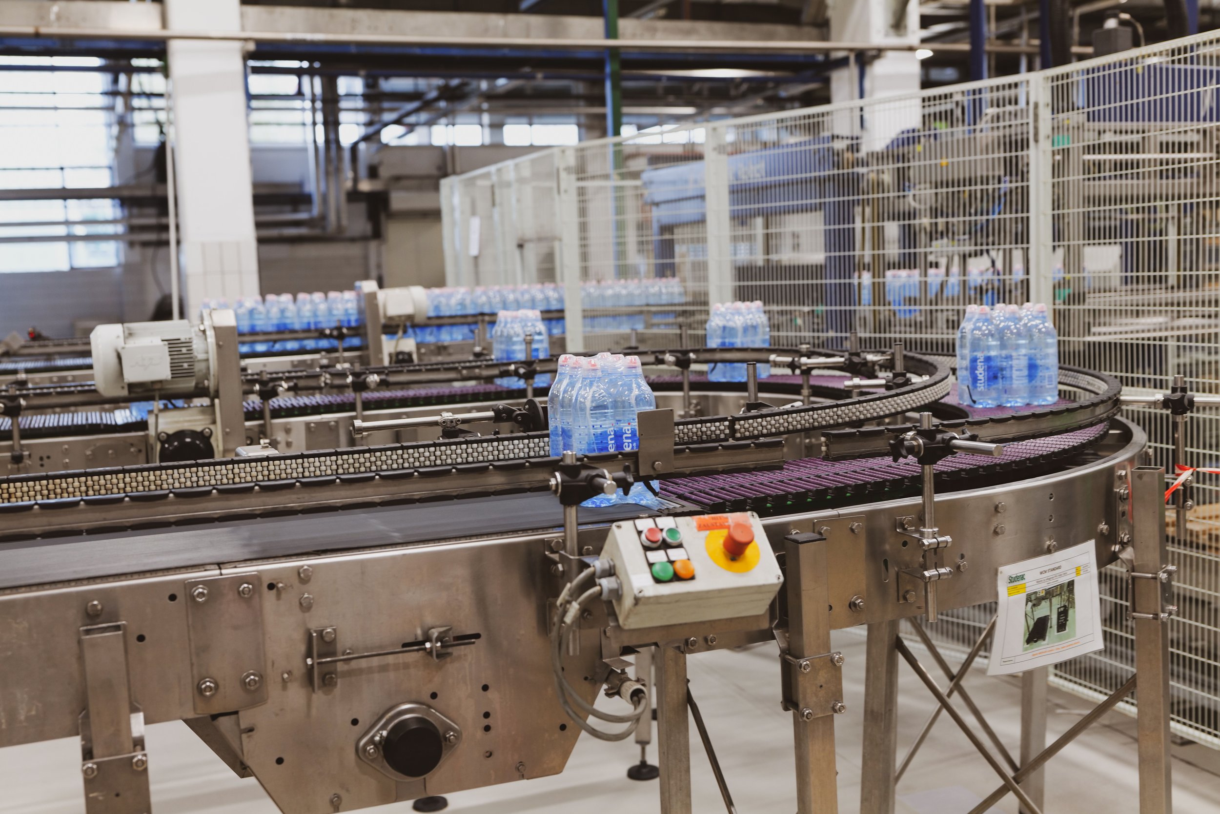 Factory conveyor line with water bottles, where defective or malfunctioning machinery can cause product liability injuries