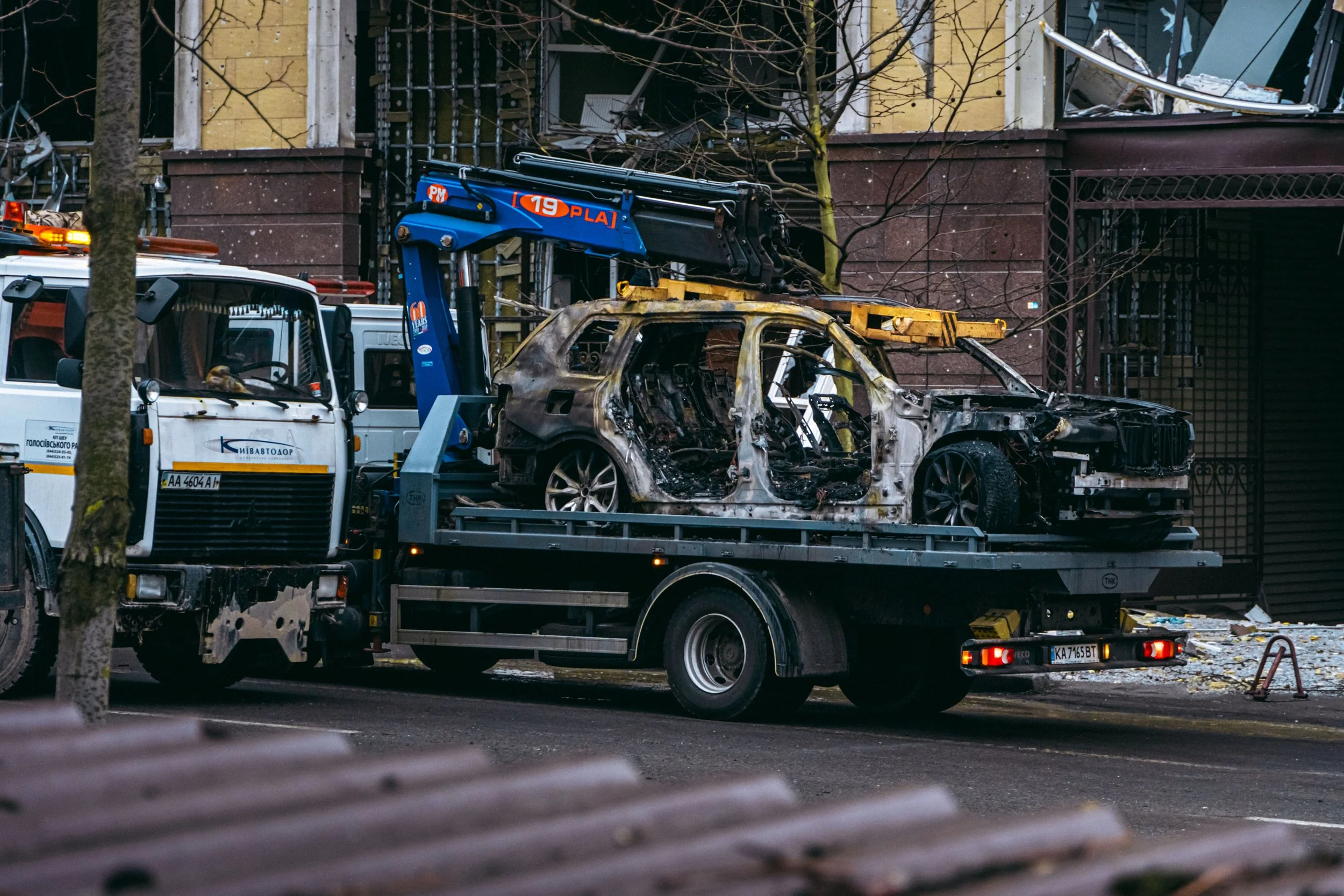 Tow truck carrying a burned-out car, wreckage from a car and truck accident handled by a personal injury firm