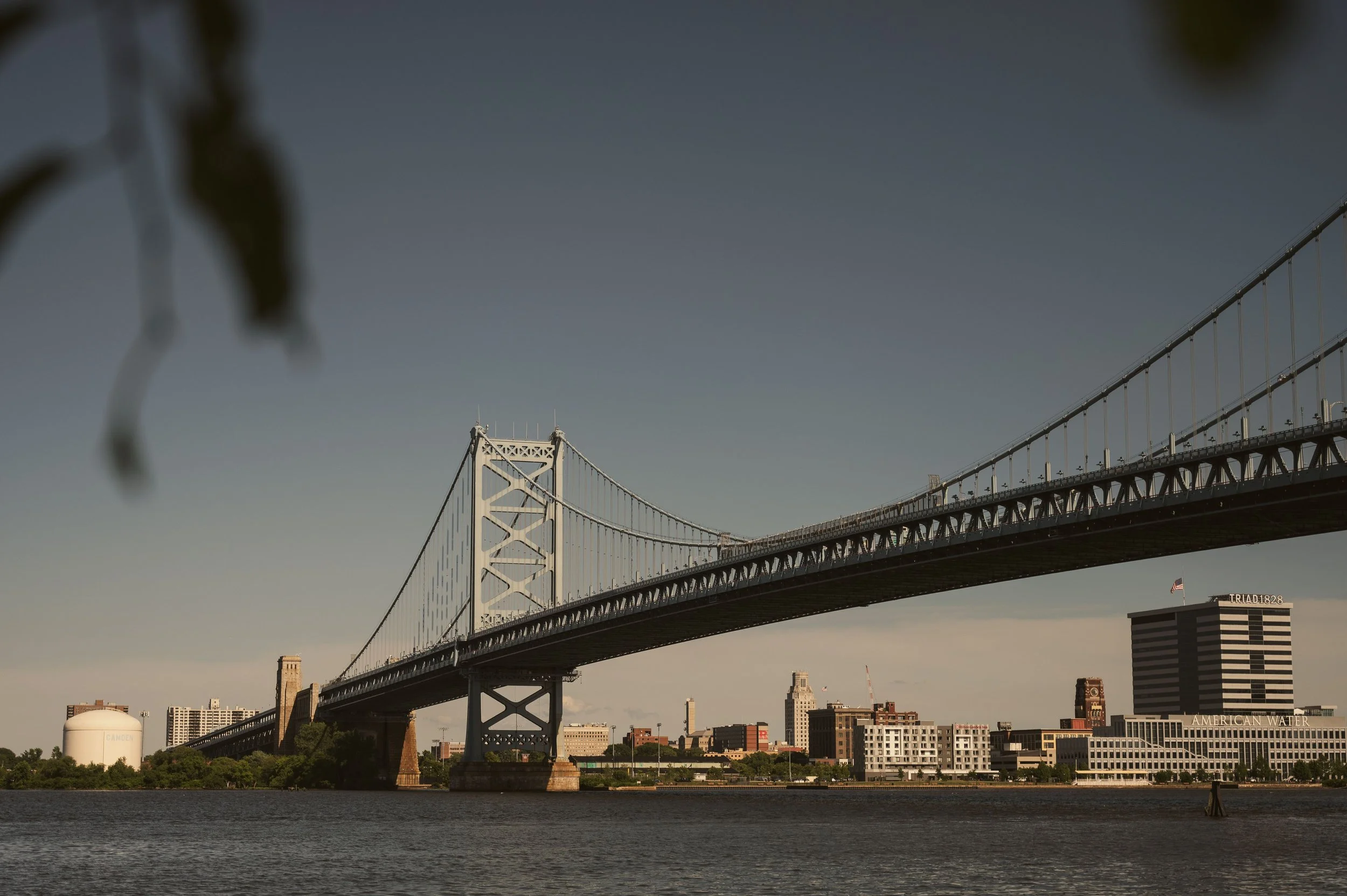 Suspension bridge over a river beside a city skyline, representing busy Trenton, New Jersey roads and traffic accidents