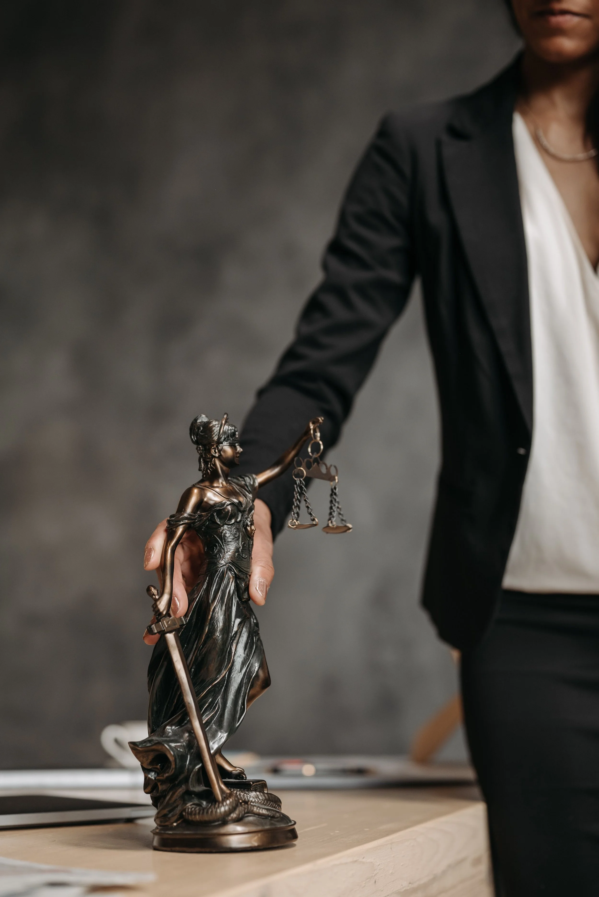 Female personal injury attorney standing next to a bronze Lady Justice statue on an office desk"