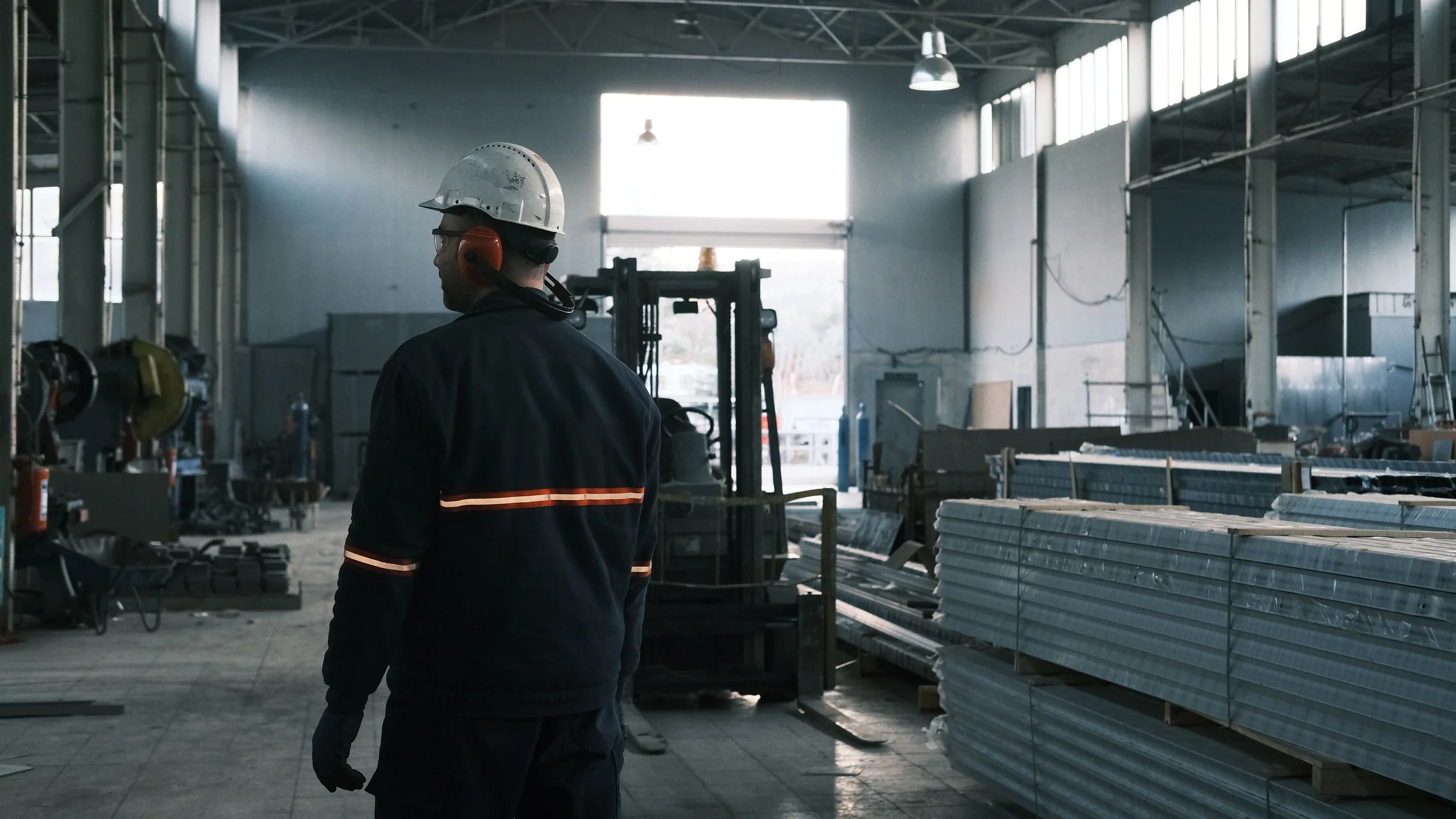 Warehouse worker in a hard hat, a facility where workplace injuries can happen near forklifts