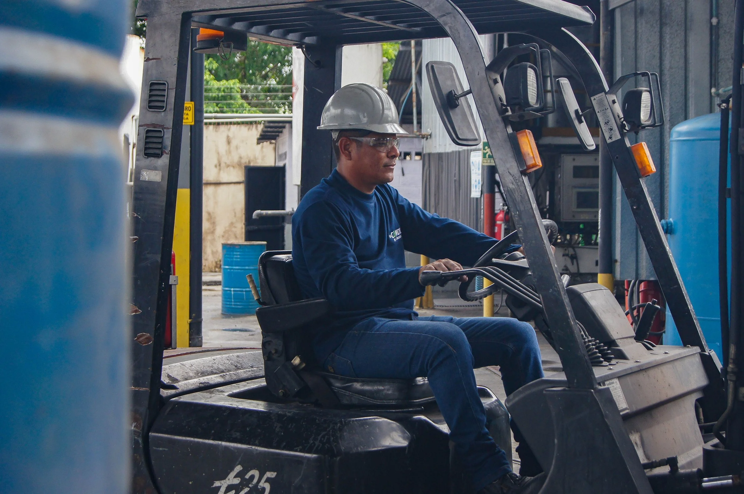 Forklift operator in a hard hat, a heavy machinery and equipment workplace accident risk in a warehouse