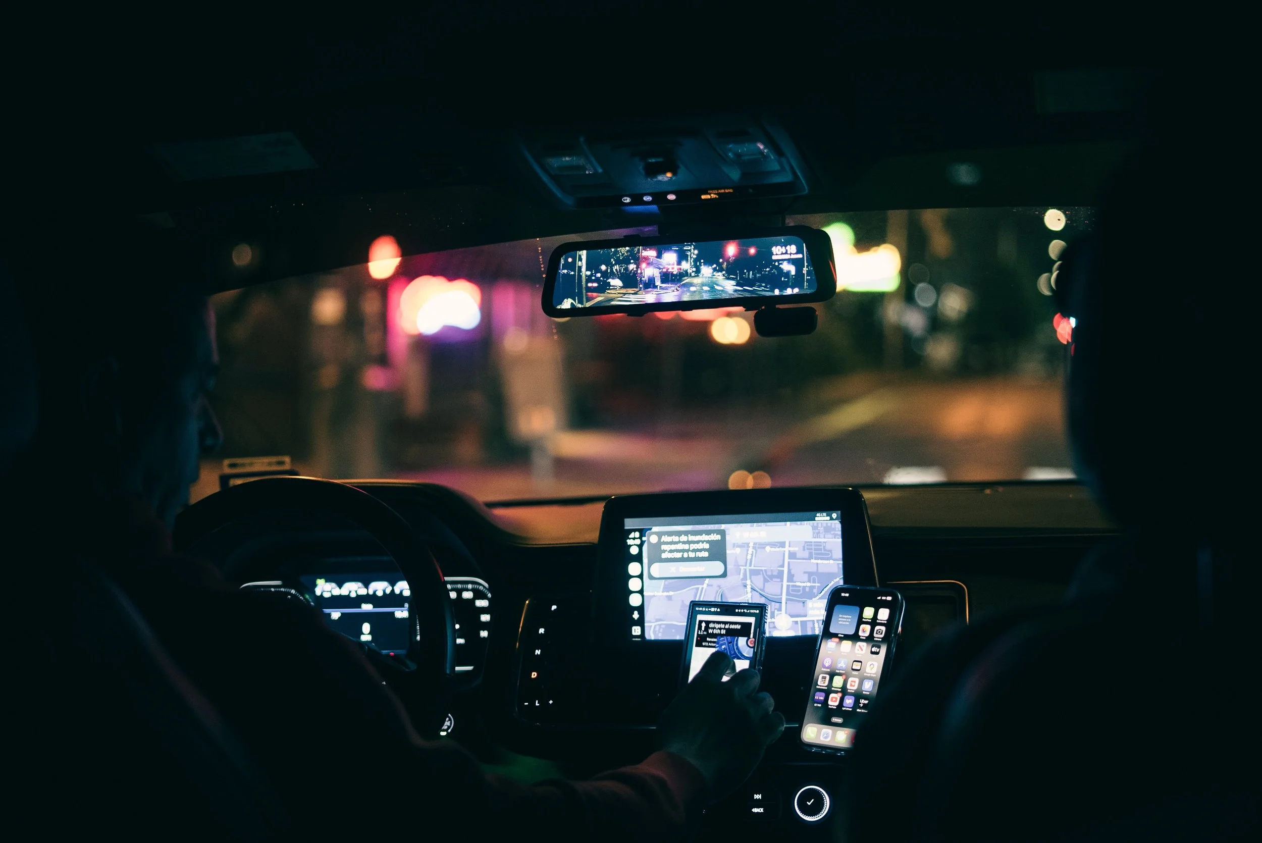 View from inside a rideshare car at night showing a navigation screen and phone, for rideshare passenger accident claims