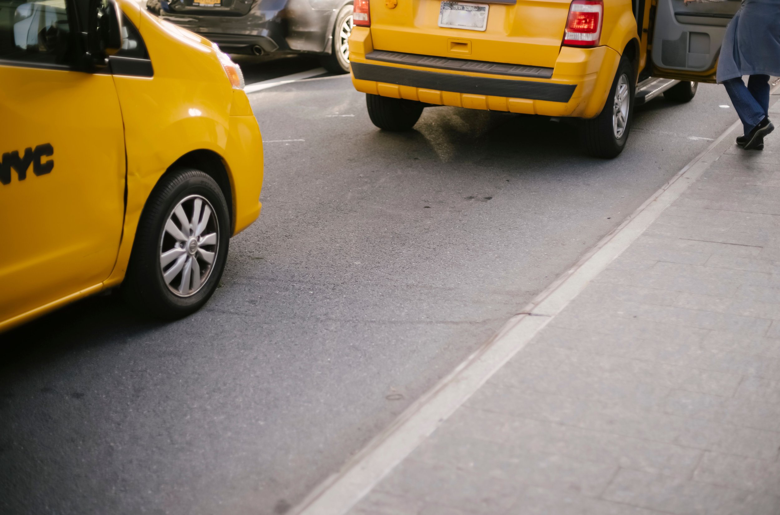 Yellow taxi cab on a city road beside traffic, representing other motorists in a rideshare accident
