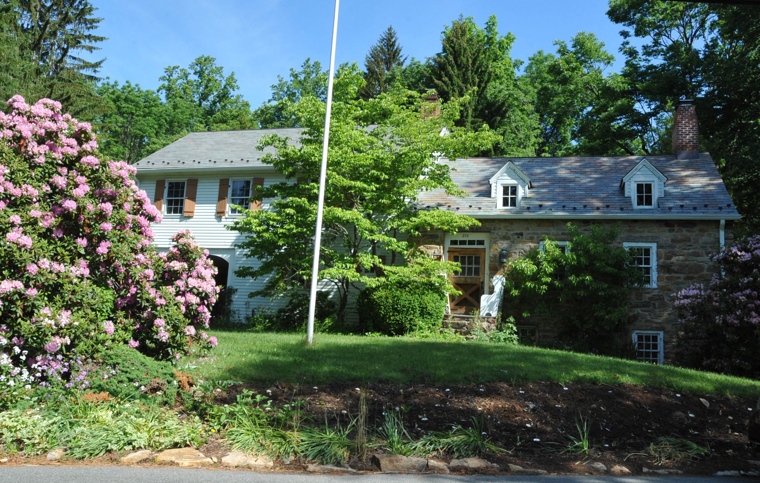 Casa histórica de piedra con un mástil y flores, un entorno acogedor para los clientes de lesiones personales de Flanders, Nueva Jersey