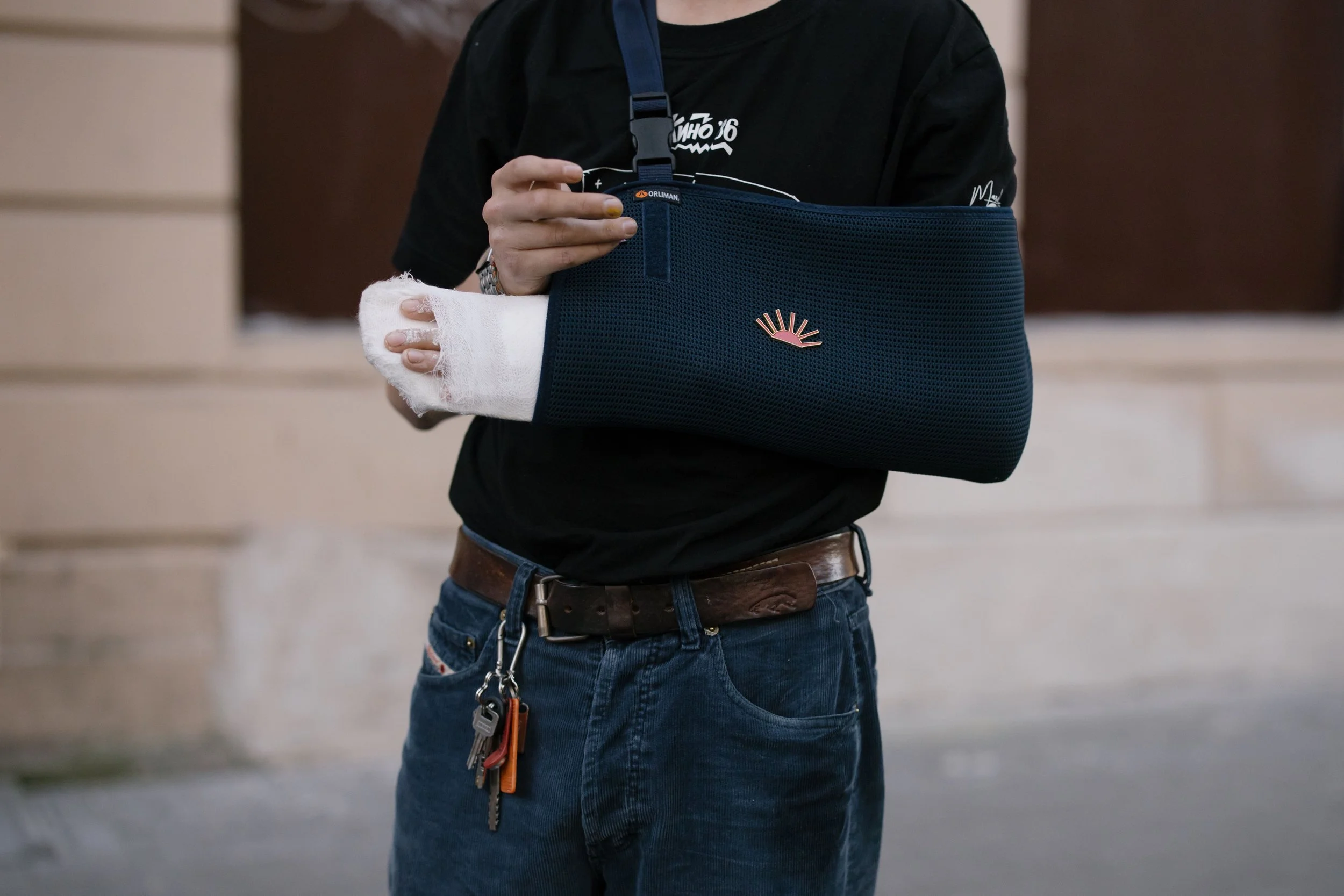 Person with a bandaged hand and arm in a blue sling, recovering from a fracture or broken bone injury