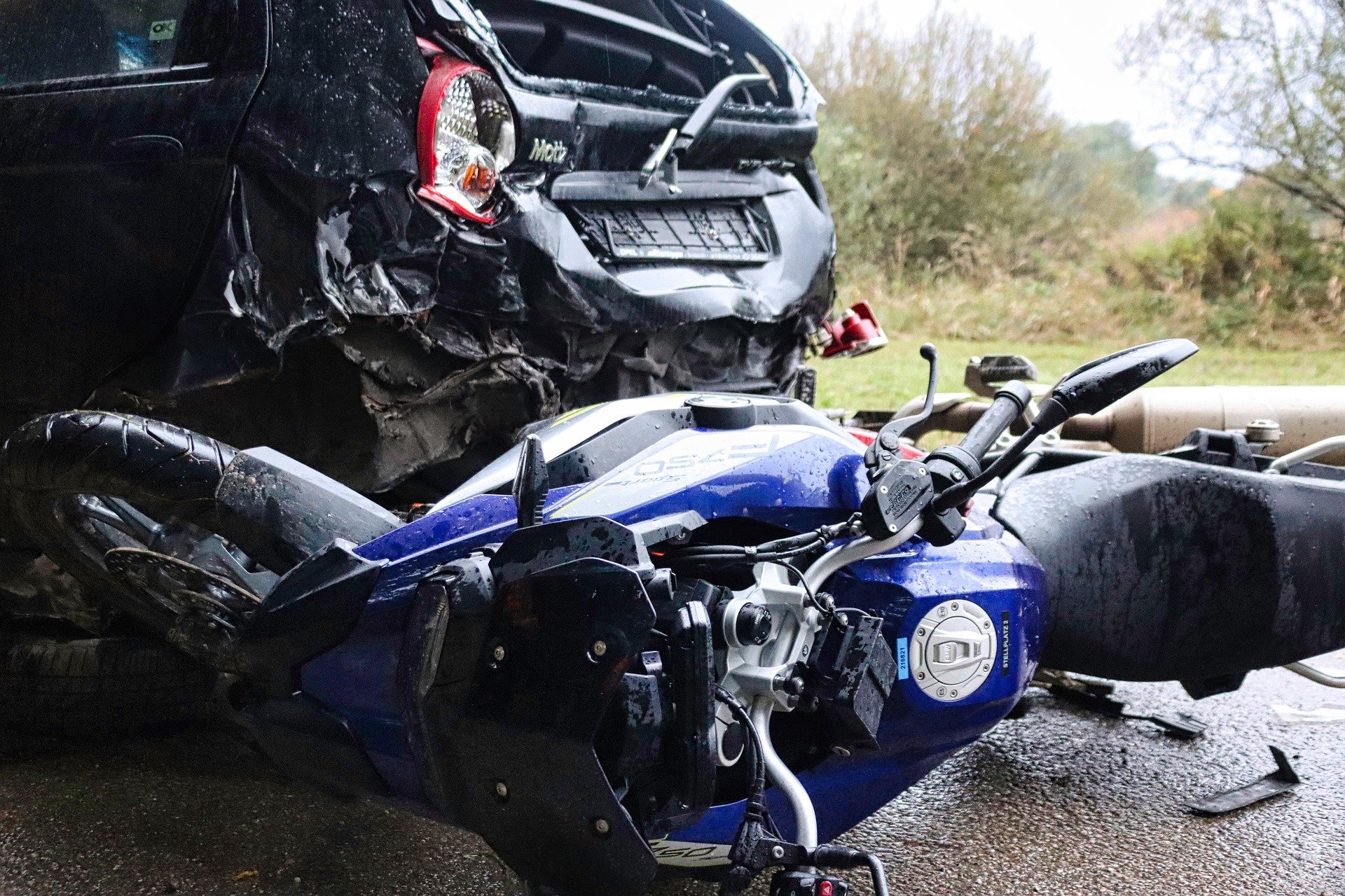 Motorcycle accident scene with a blue motorcycle crashed beside a damaged car, representing motorcycle injury claims