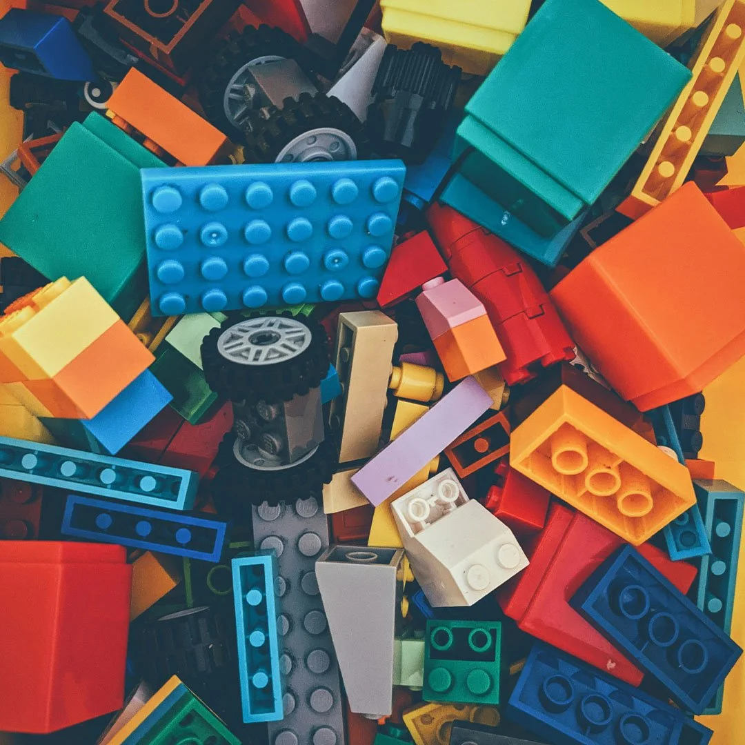 Colorful assorted LEGO bricks and pieces, including wheels and blocks.