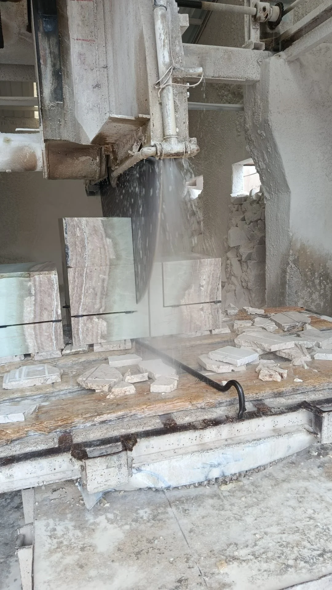Marble slabs being cut in a workshop using a wet saw, with scraps of marble around.