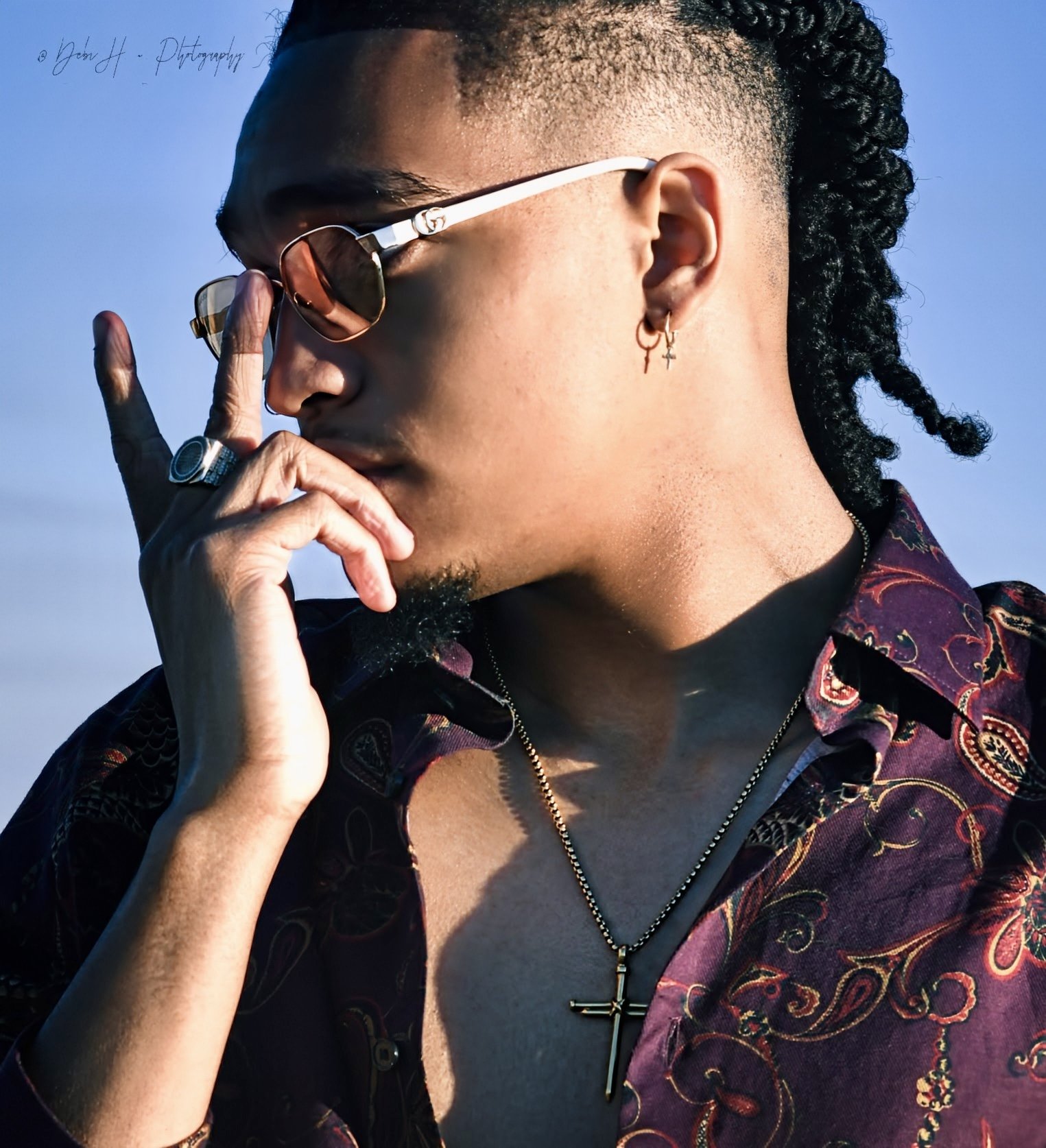 Man with sunglasses and cross necklace looking to the side