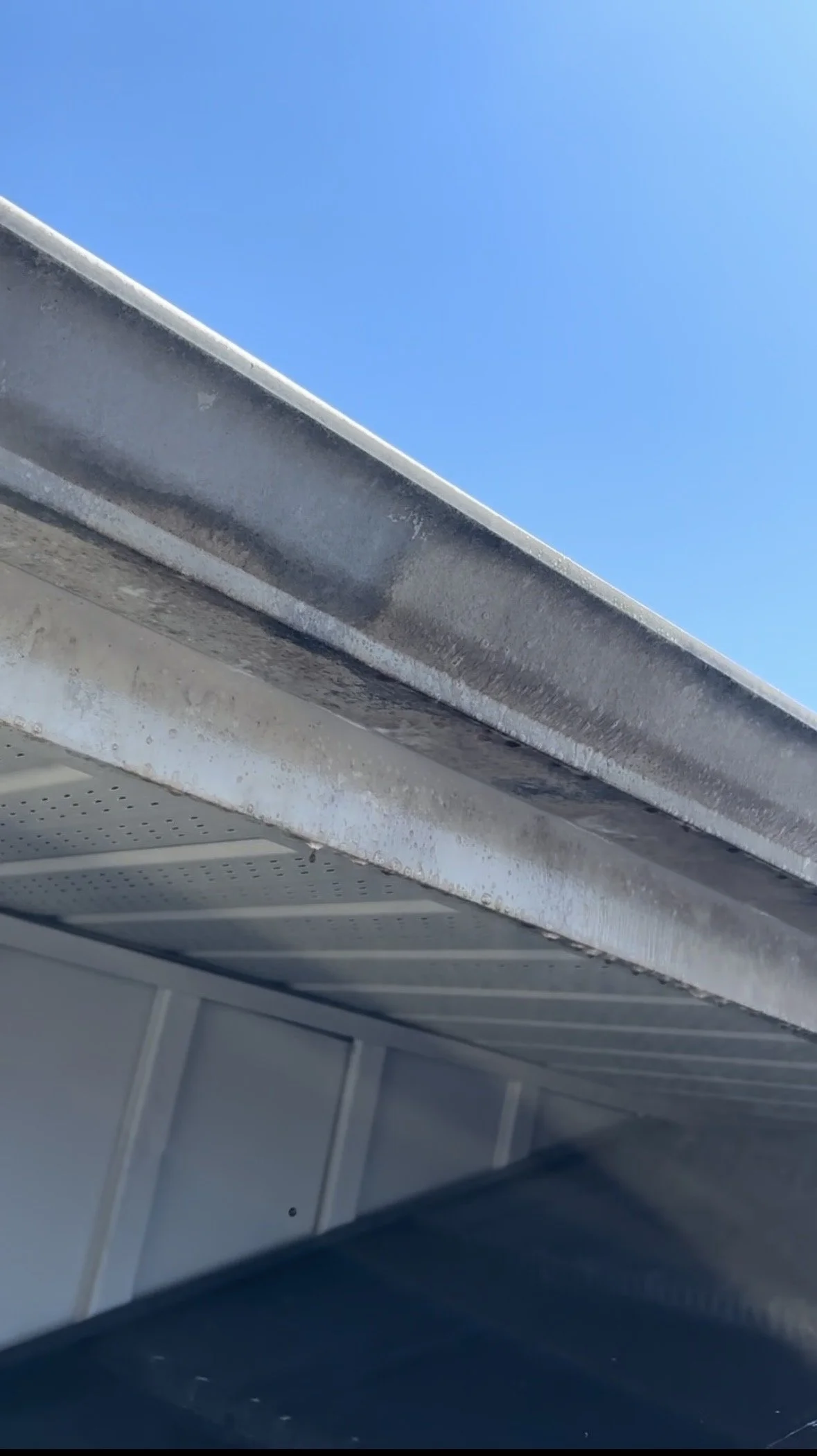 Close-up of a metal gutter with a clear blue sky in the background.
