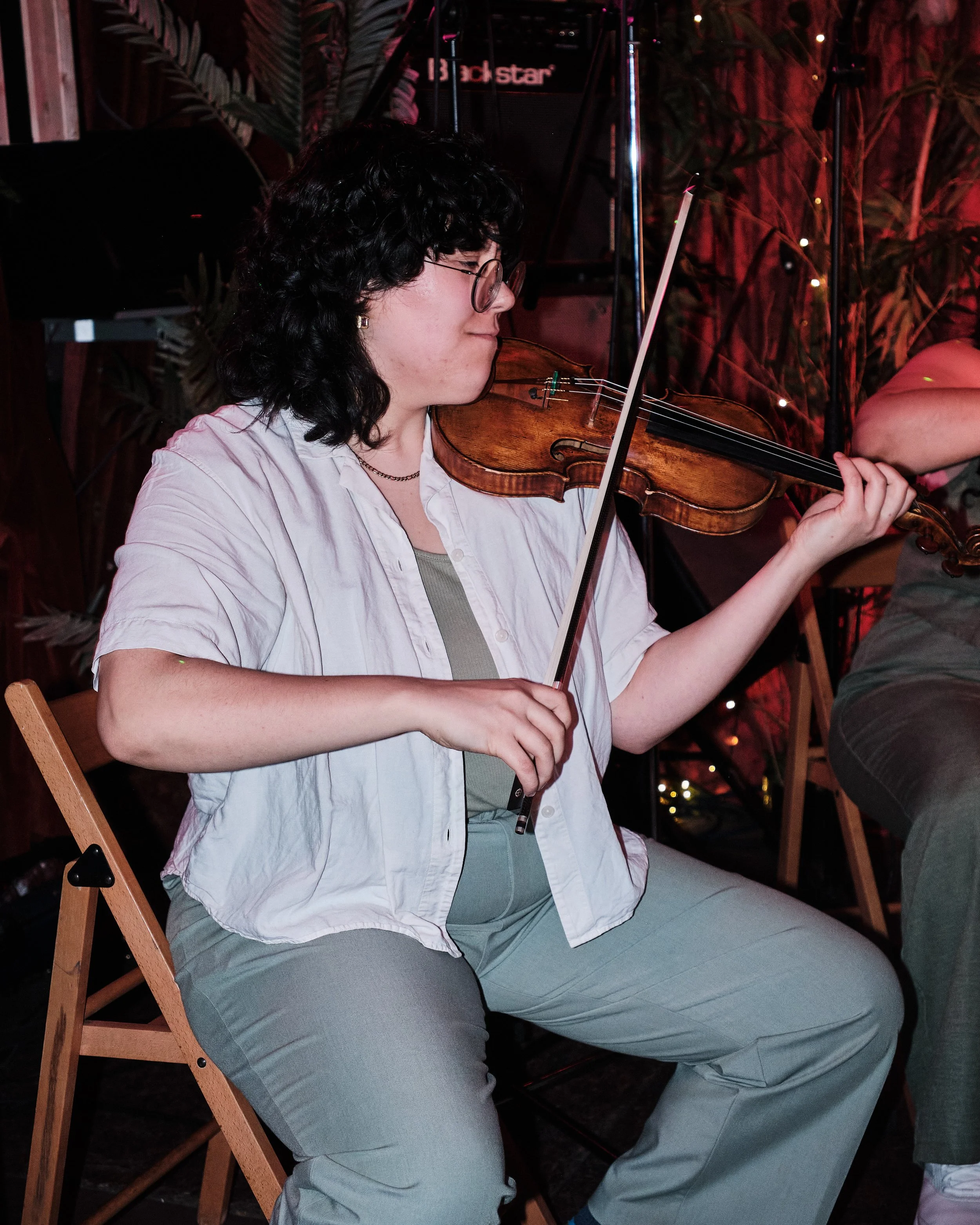 Person playing violin surrounded by musical equipment.
