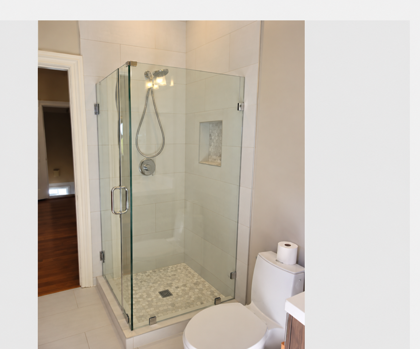 Custom frameless clear glass shower enclosure with chrome hardware, hinged door, and fixed panels.