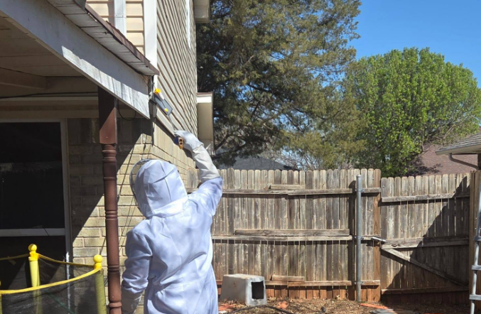 Pest control technician applying exterior treatment to home in Edmond