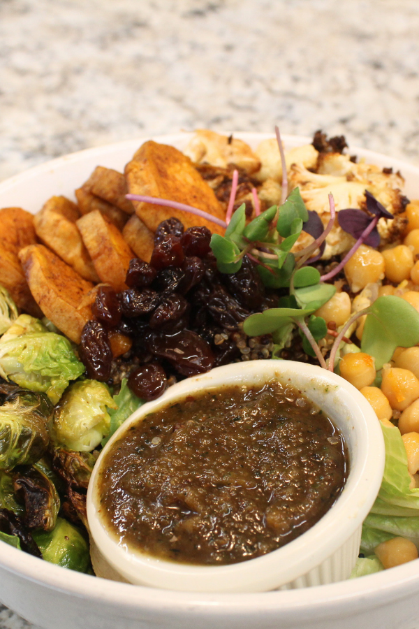 Roasted brussel sprouts and sweet potato rounds, marinated chickpeas, quinoa, and pickled raisins served atop fresh greens with a ramekin of herby pecan sauce