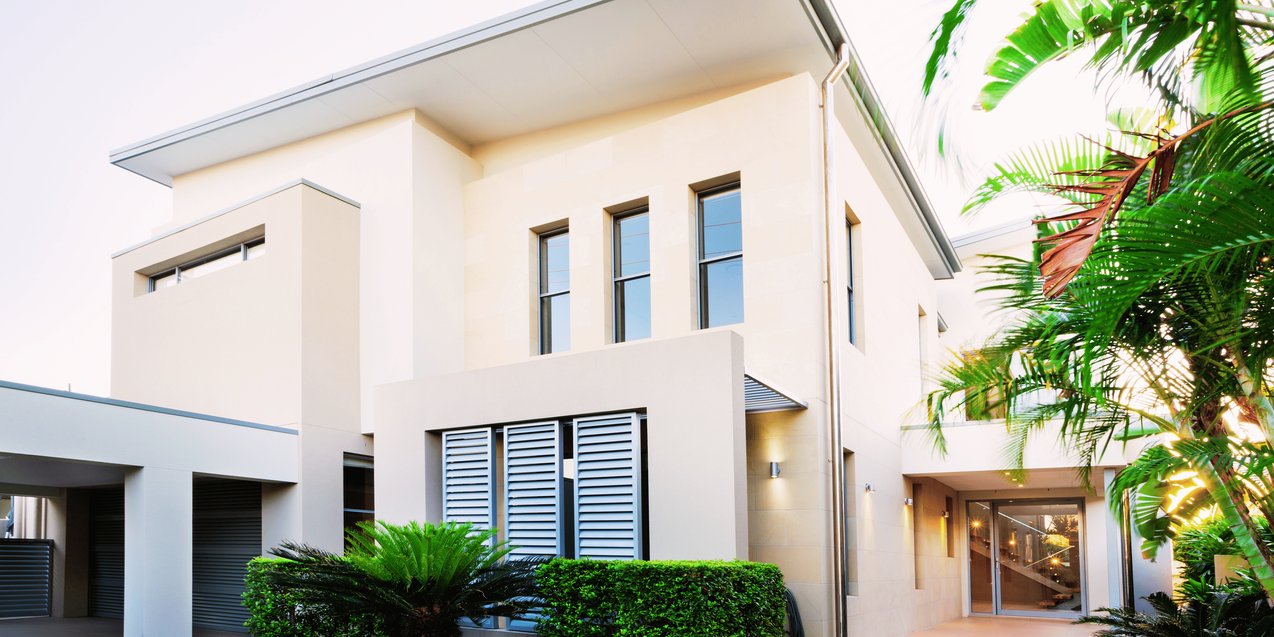 Villa moderne avec piscine, grandes fenêtres, ciel bleu et structure architecturale contemporaine.