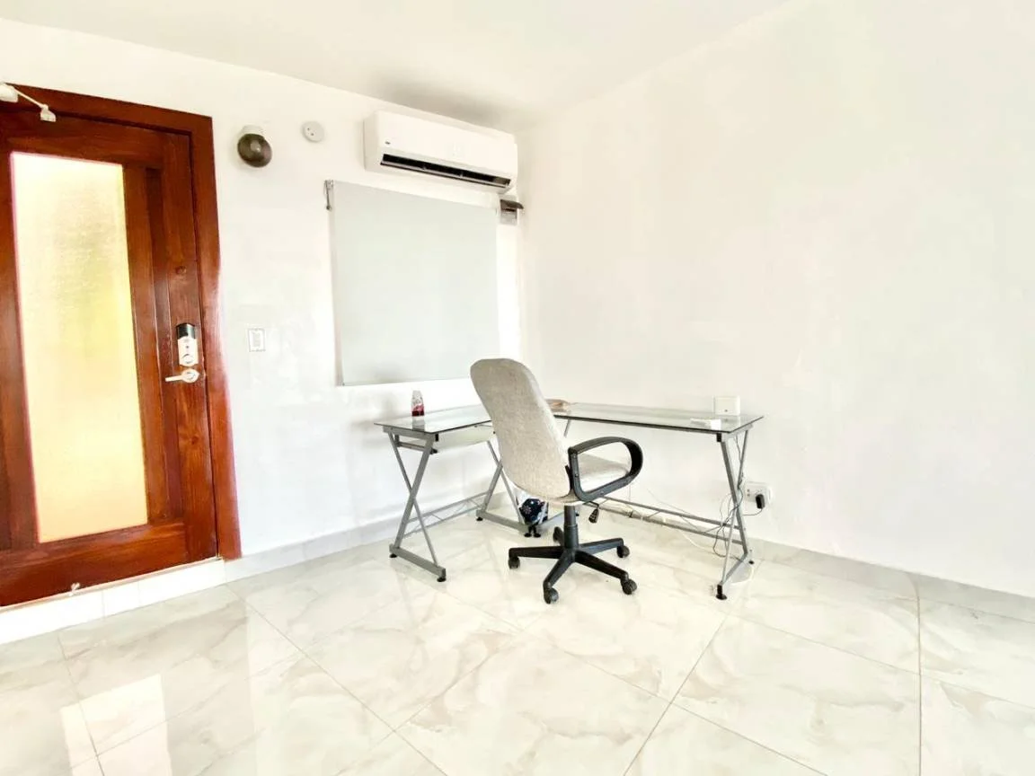 Bureau minimaliste avec chaise, porte en bois, tableau blanc et climatisation.