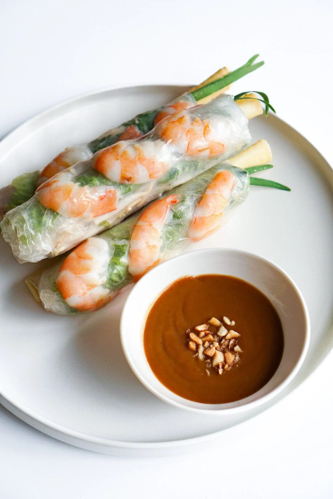Freshly rolled shrimp spring roll with a side of peanut sauce topped with peanuts