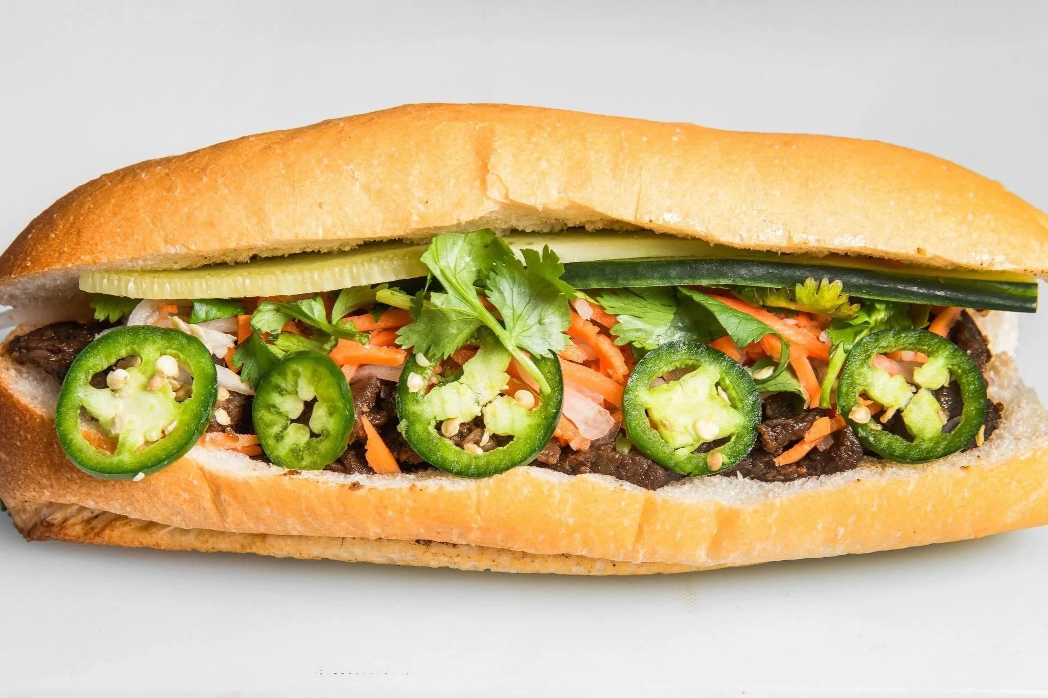 Crispy Fresh Toasted Vietnamese Sandwich Banh Mi with choice of meat, grilled chicken, pork, tofu, beef including vietnamese ham with cucumber, cilantro, jalapeño, pickled carrot daikon, pate, garlic spread