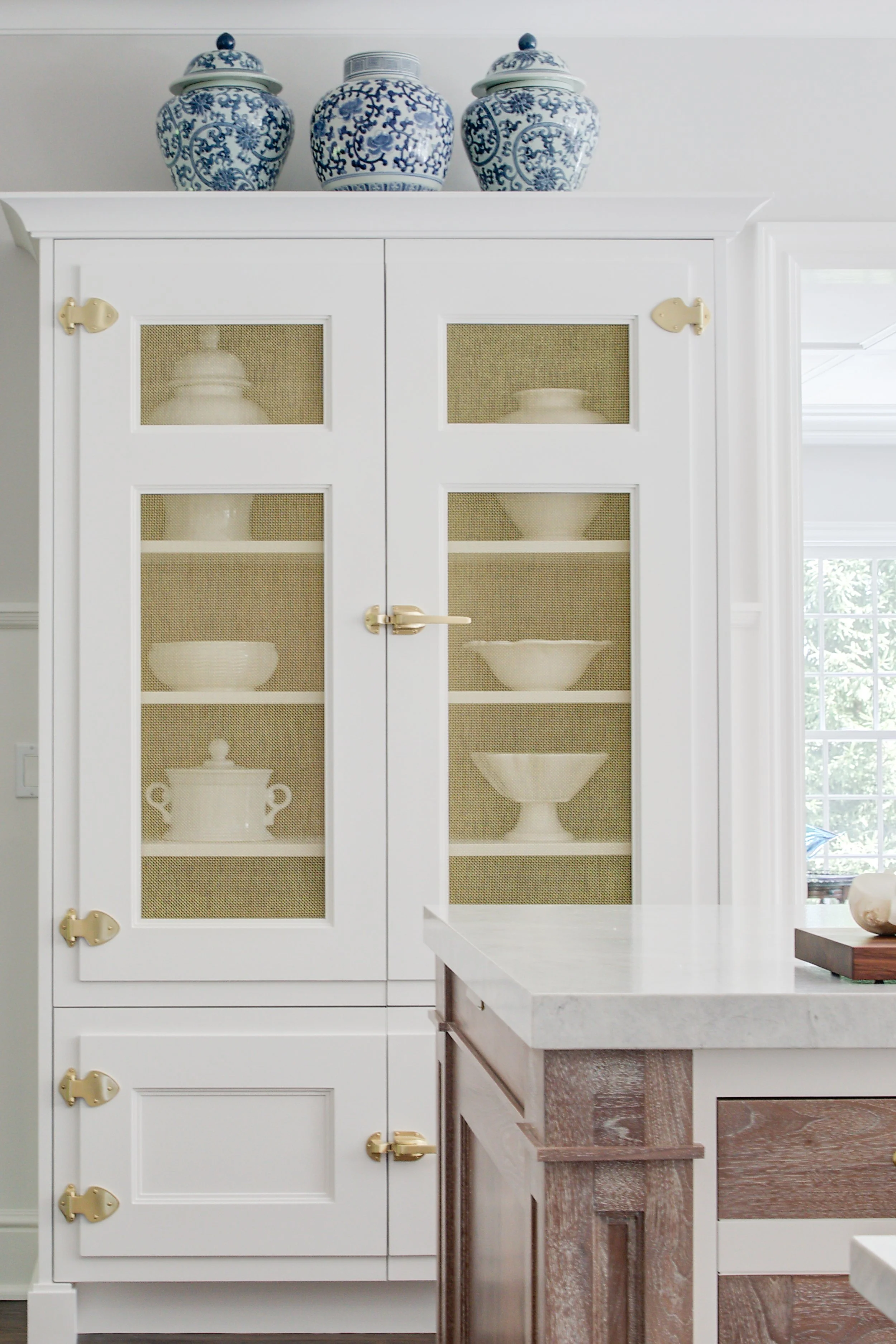 High-end kitchen and interior design in Fairfield County CT & Charlotte, NC: custom white pantry cabinet with brass hinges and blue-and-white jars, New Canaan CT.
