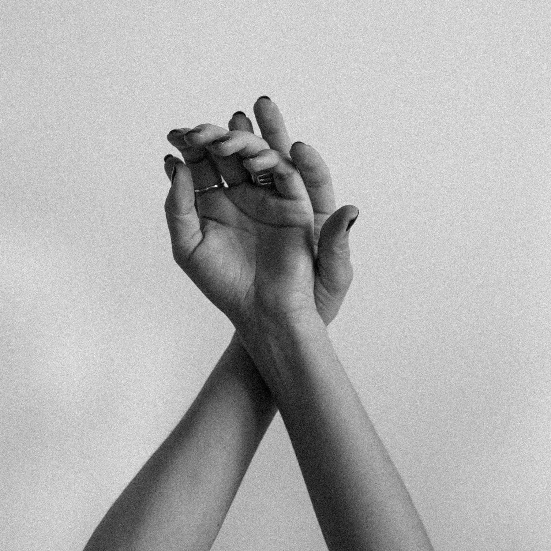 Two hands gently holding each other, with one hand's fingers intertwined with the other's.