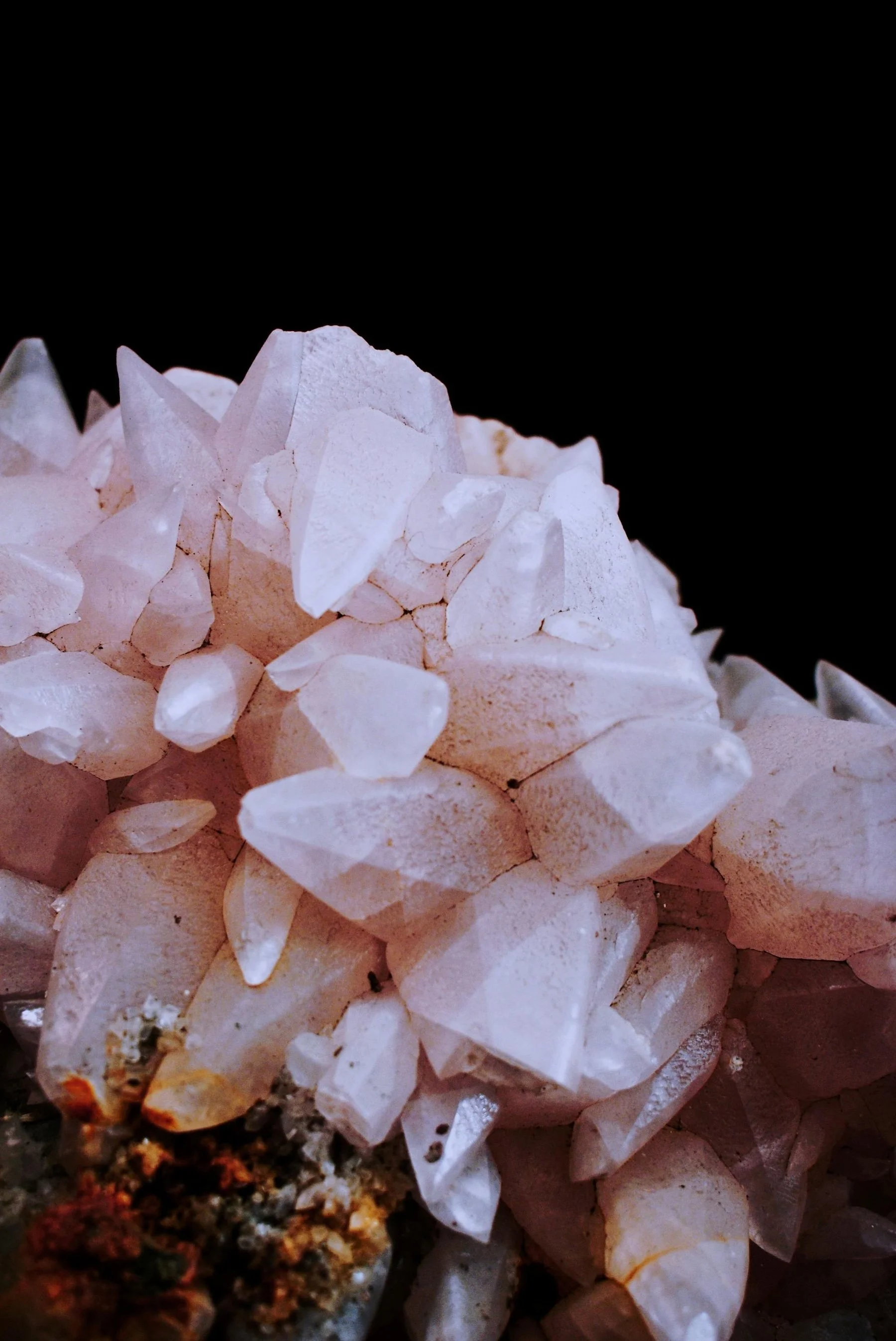 Close-up photograph of a cluster of white quartz crystals against a black background.