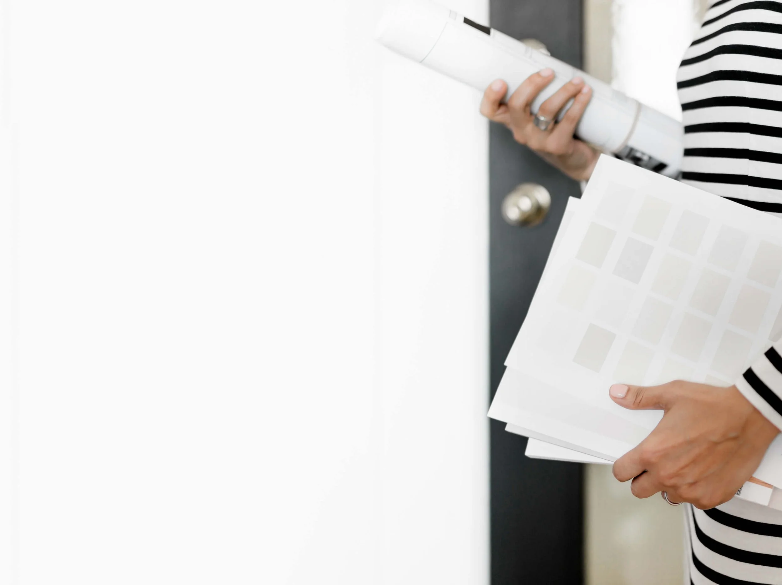 High end kitchen and interior design Fairfield County CT & Charlotte, NC: person holding rolled plans and a finish swatch deck during interior design planning.