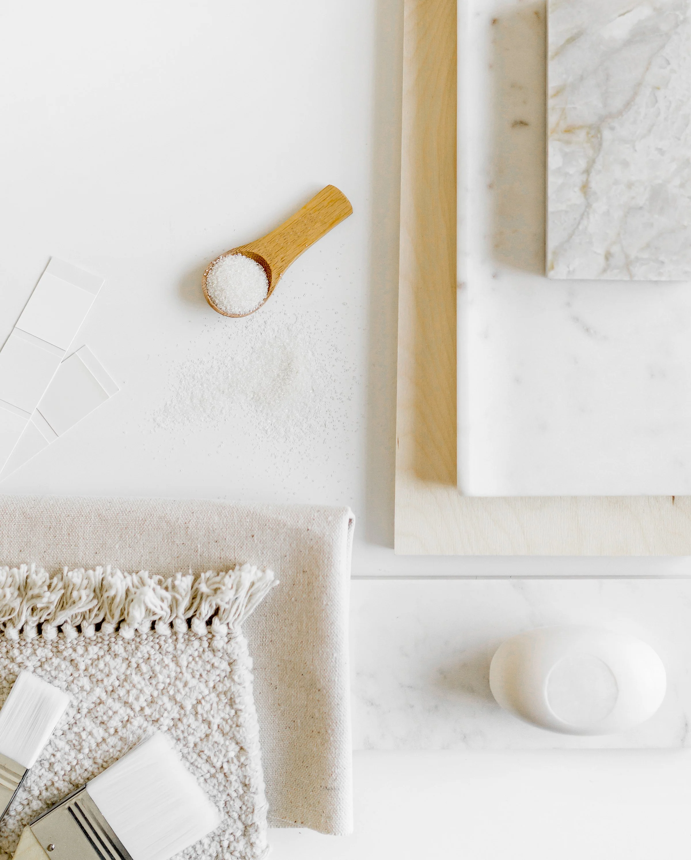 Neutral flat lay with a texture swatch, stone sample, and minimal styling elements on a light surface.