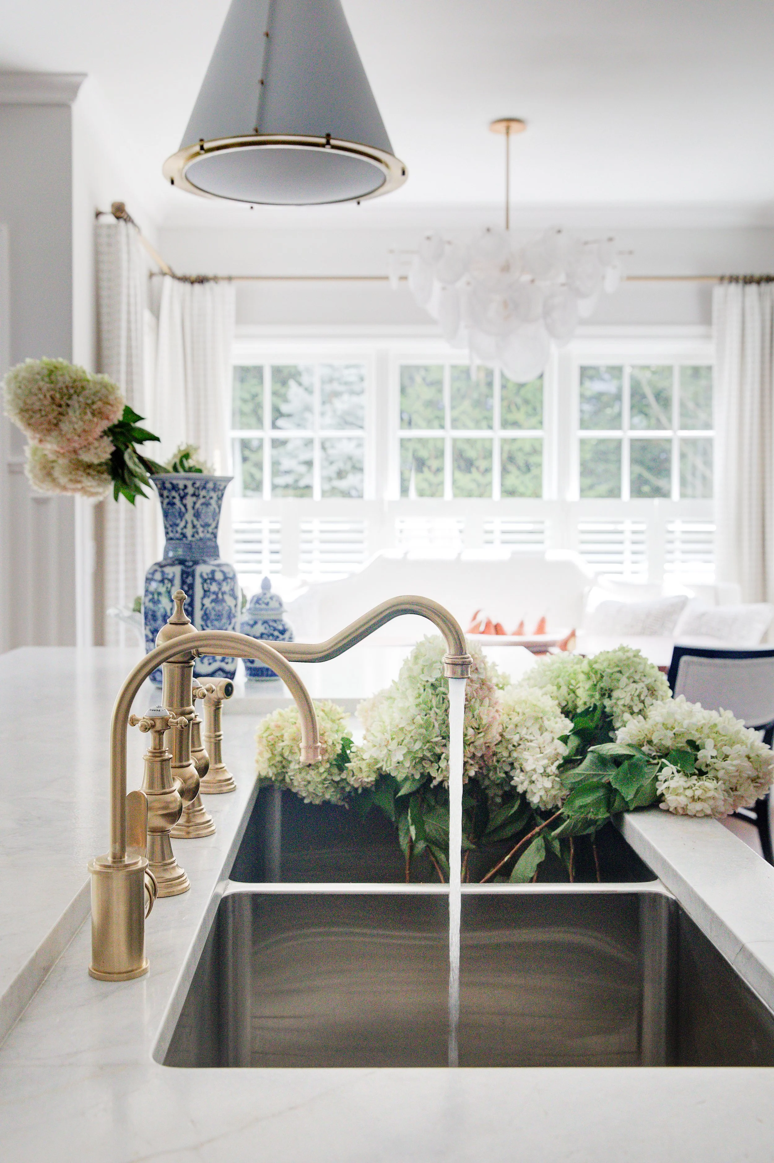 High-end kitchen and interior design in Fairfield County CT & Charlotte, NC: brass faucet over marble island sink with hydrangeas in New Canaan, CT.