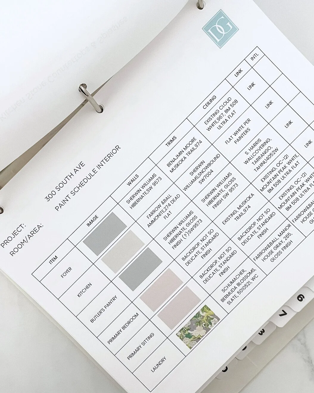 Interior paint schedule sheet with color and finish details for various rooms in a house, attached to a binder with numbered tabs.