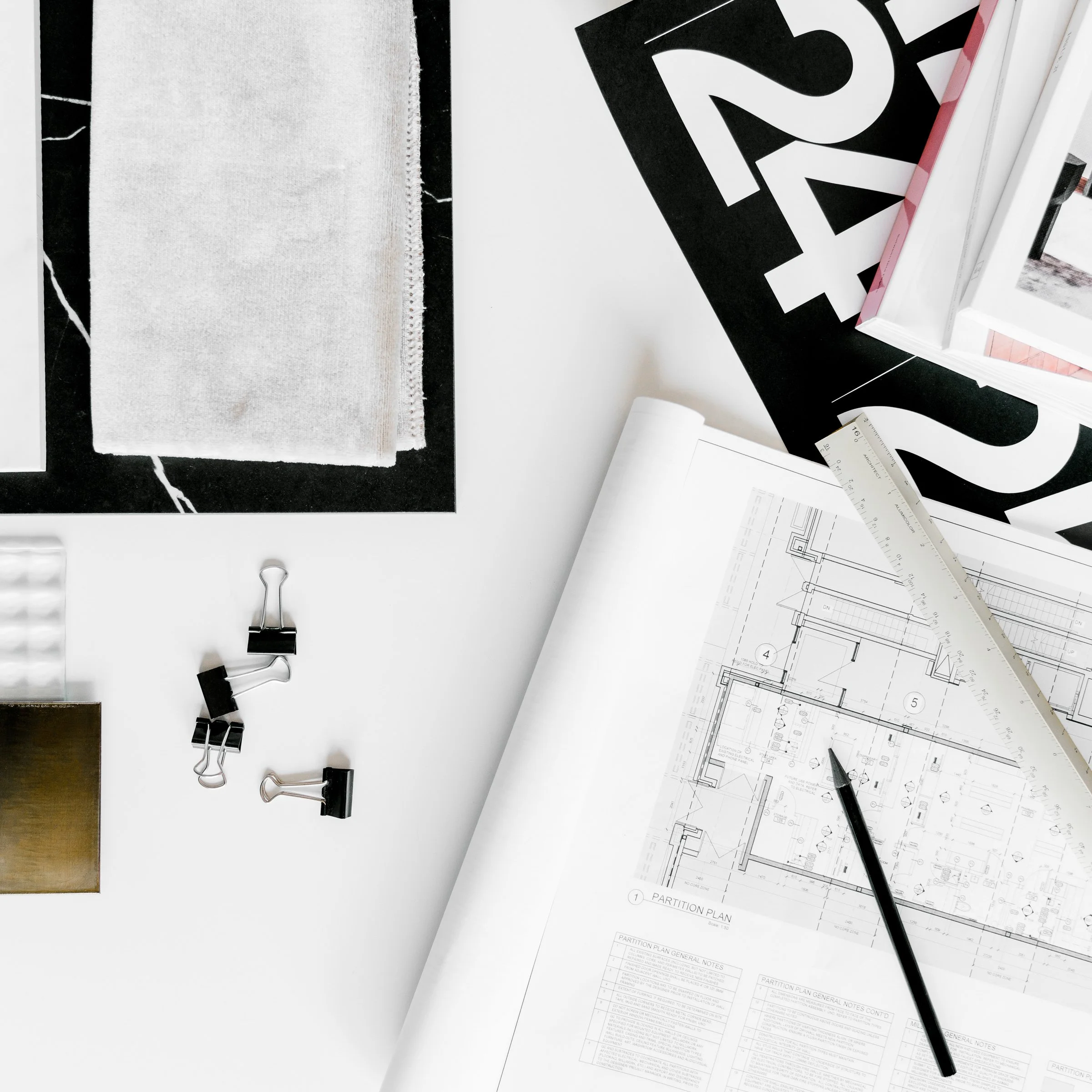 Close-up of an architectural plan with a ruler and pencil on a clean white desk.