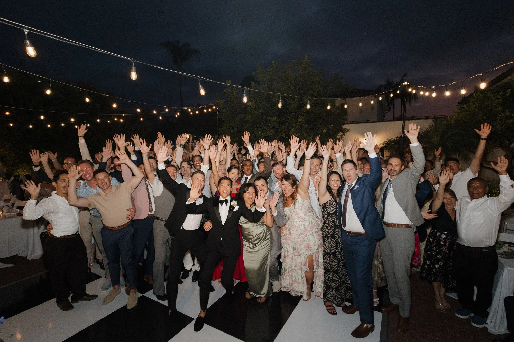 Overhead group photo of all guests cheering on the dance floor at Ryan and Sean's wedding