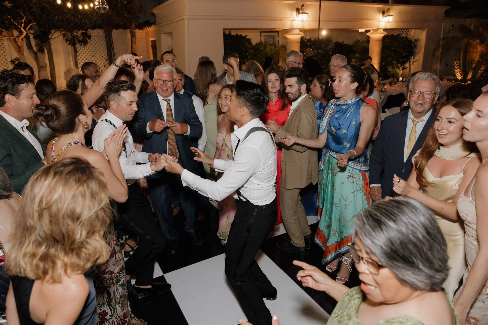 Packed dance floor with guests dancing around a groom at Darlington House