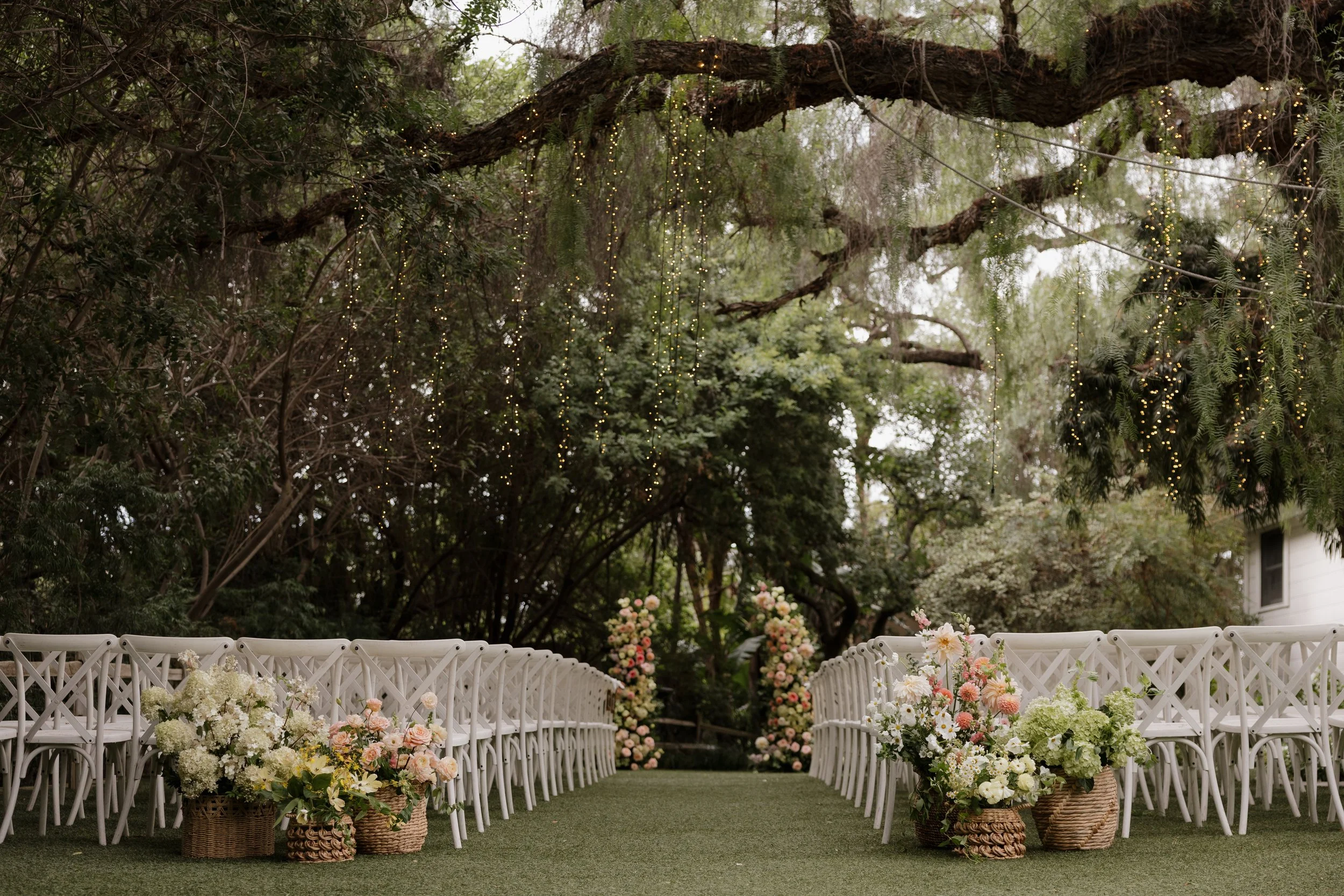 Ceremony site with white chairs, floral arrangements and oak trees at Green Gables Wedding Estate