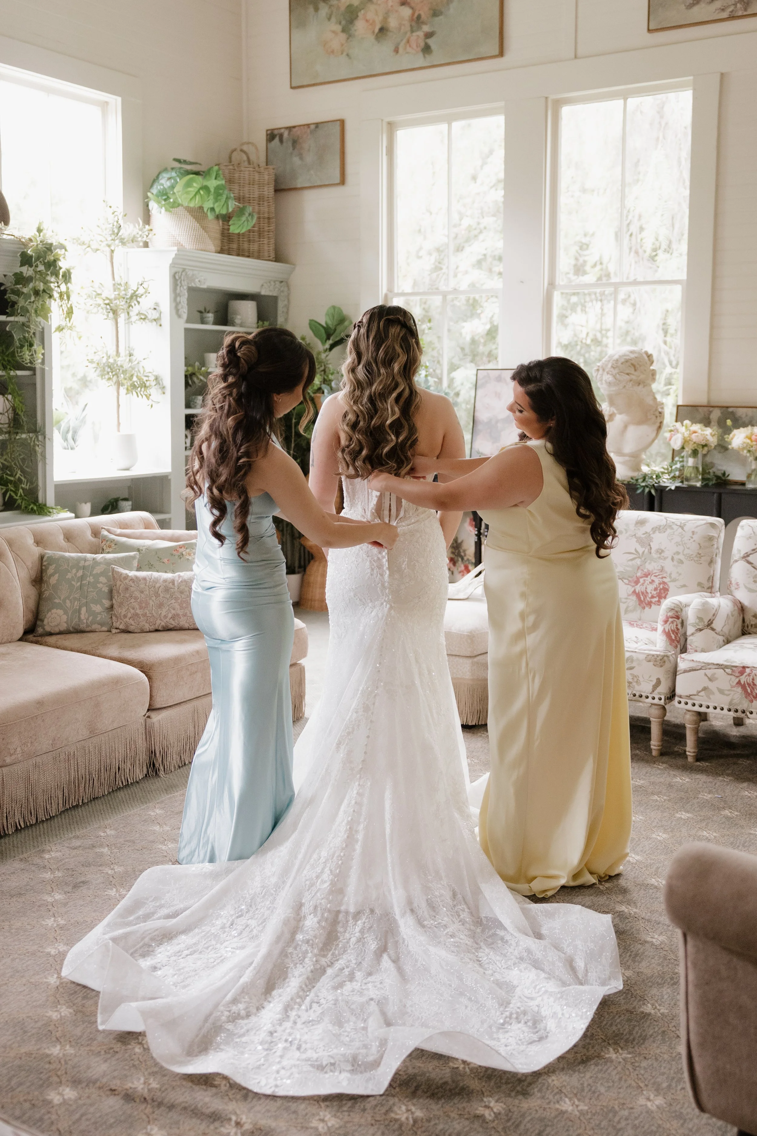 Bridesmaids helping Nancy into her lace wedding gown in the Green Gables Bridal Salon