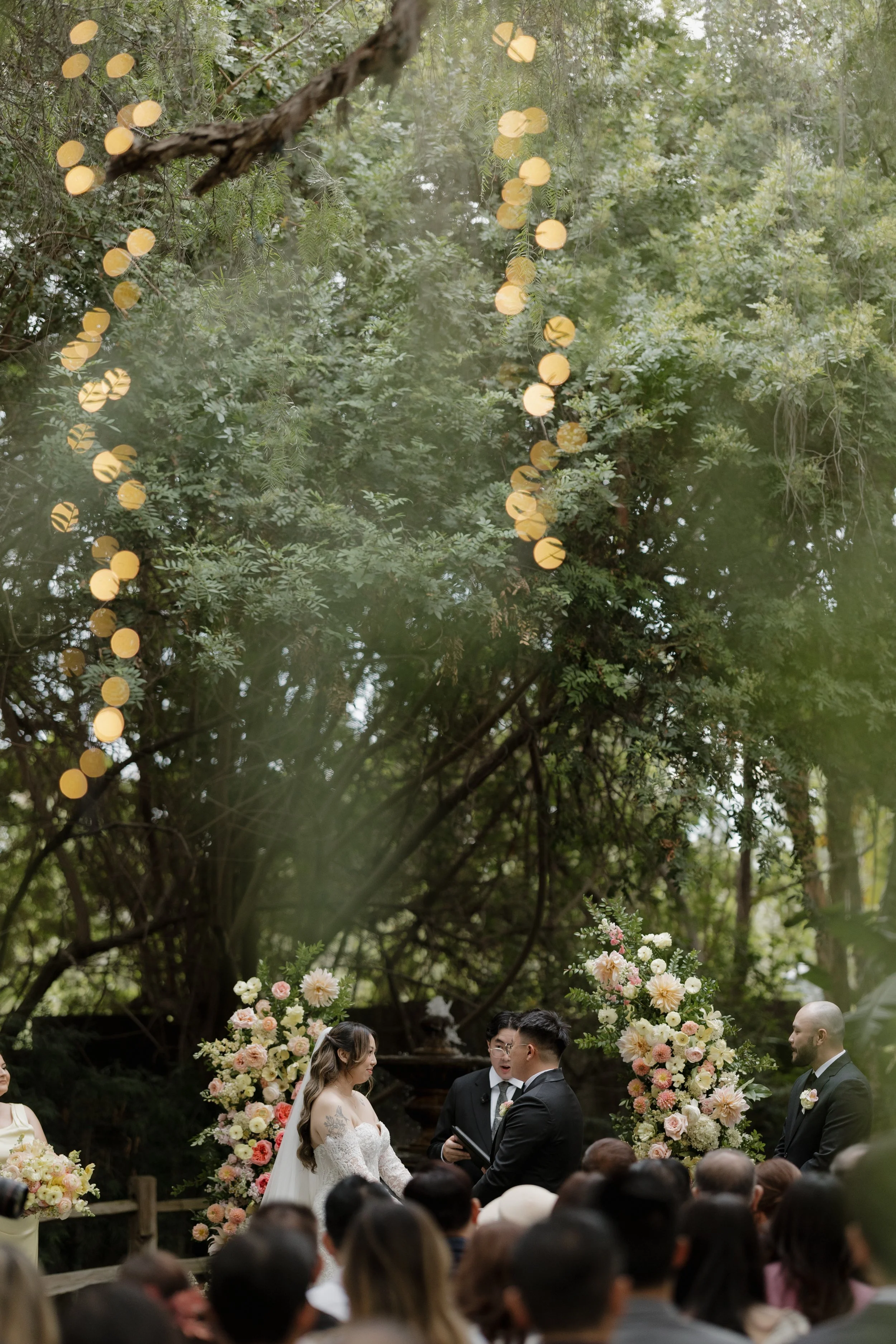 Wide view of guests watching Nancy and Ken's ceremony beneath the oak canopy at Green Gables