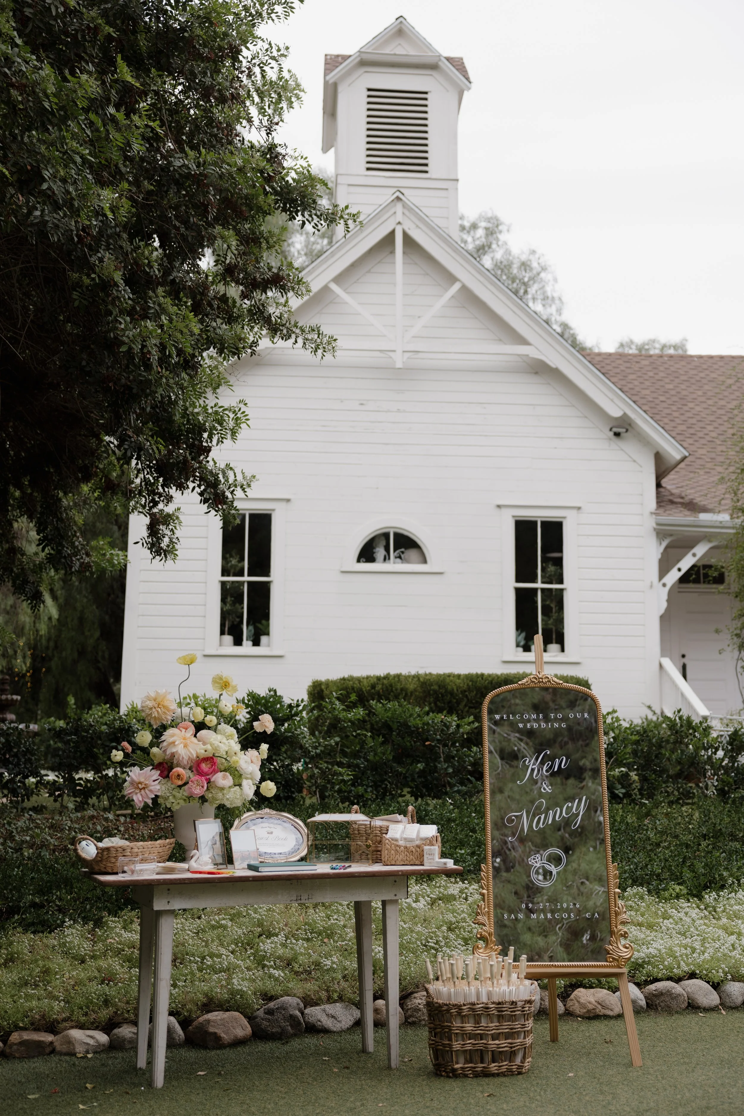 White schoolhouse with a floral welcome table at Green Gables Wedding Estate in San Marcos