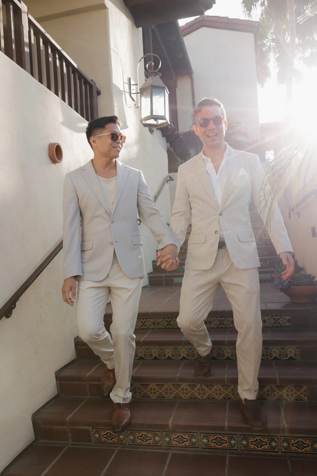 Ryan and Sean holding hands walking down Spanish-tiled stairs at Estancia La Jolla