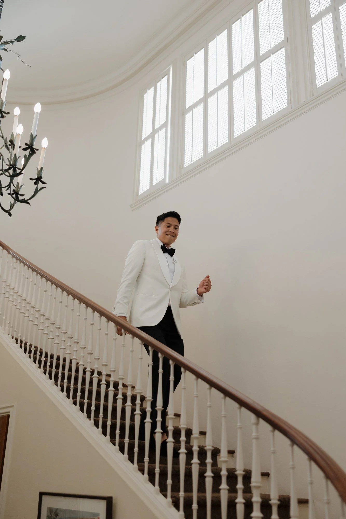 Ryan walking down the curving staircase in his white tuxedo at Darlington House