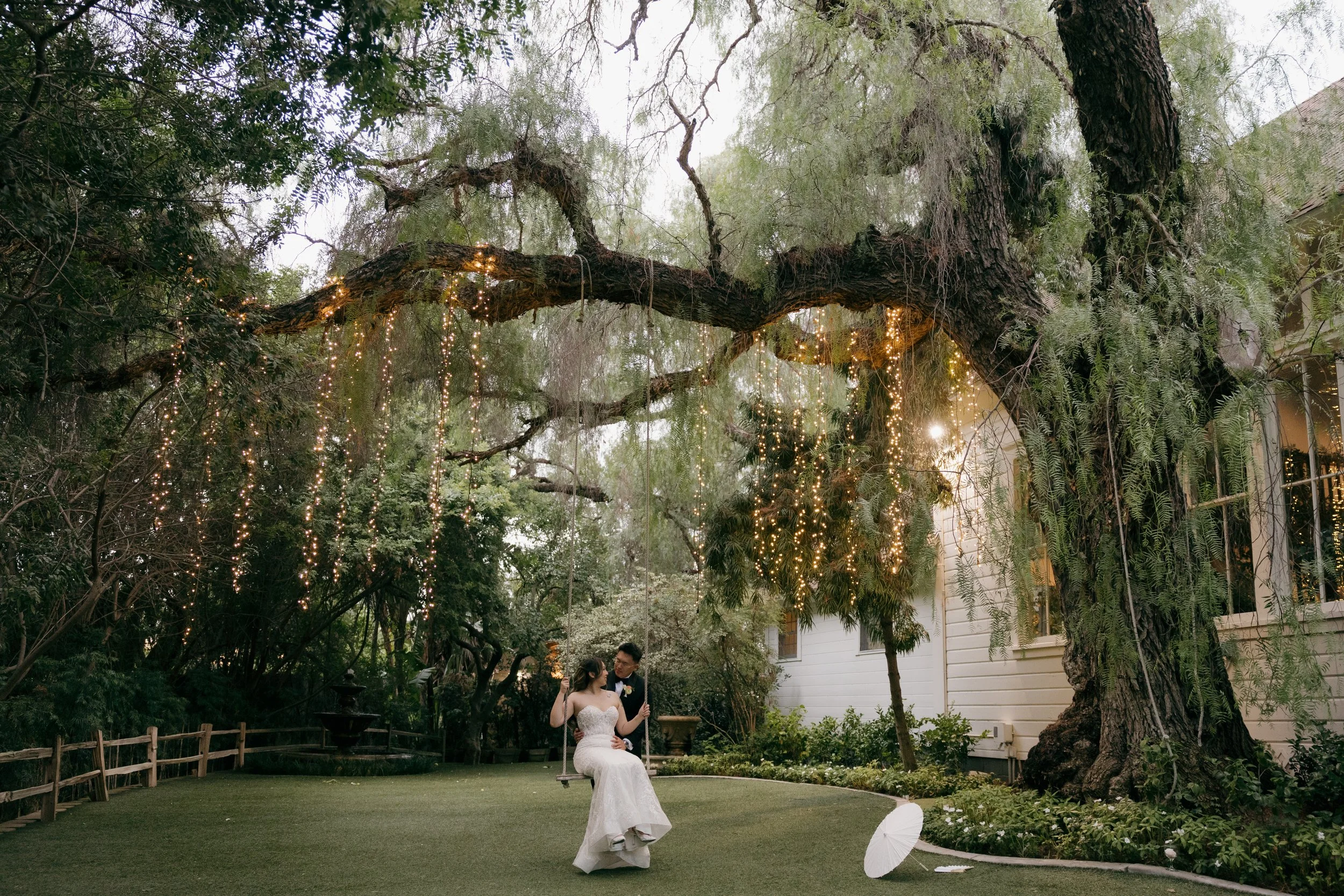 Nancy and Ken beneath a sprawling oak strung with lights at sunset in North County San Diego