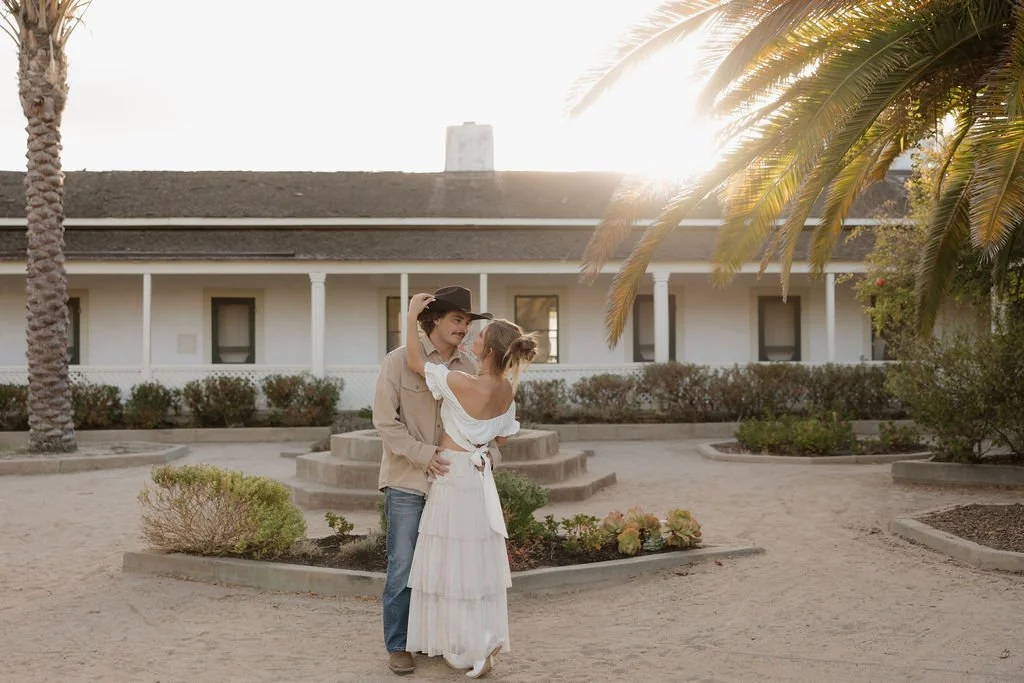 Couple embracing in the ranch house courtyard at golden hour