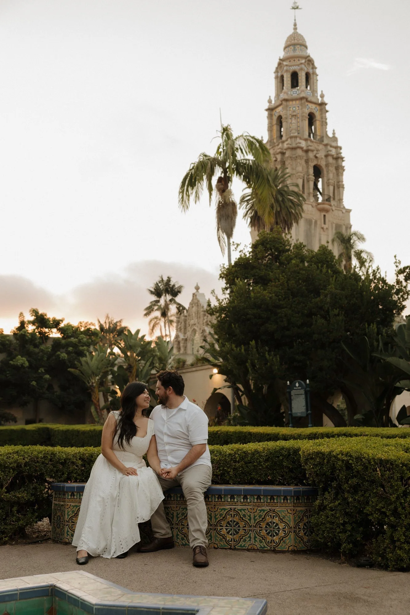 Couple sitting on a tiled bench in front of the California Tower at Balboa Park