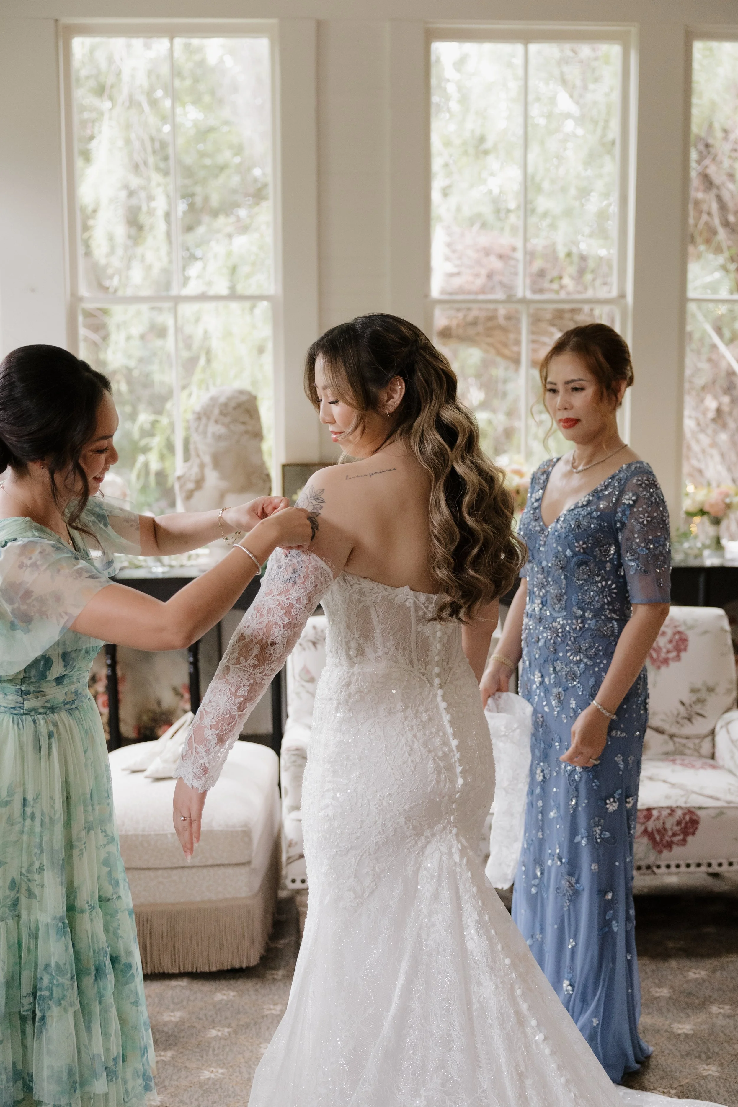 Nancy's mom and a loved one buttoning her wedding gown in the Bridal Salon
