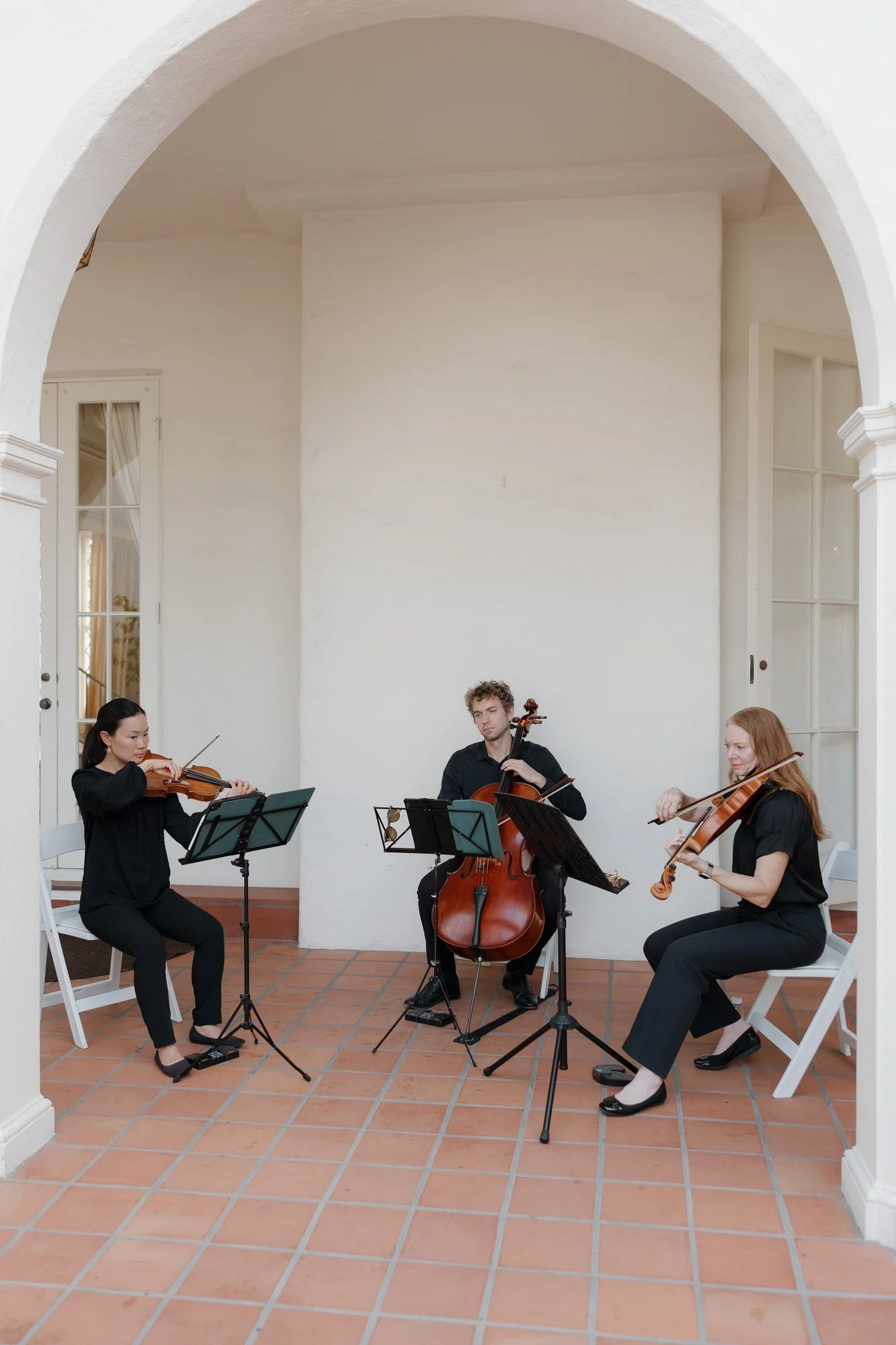 Caprice Strings trio playing under a white arch at Darlington House wedding