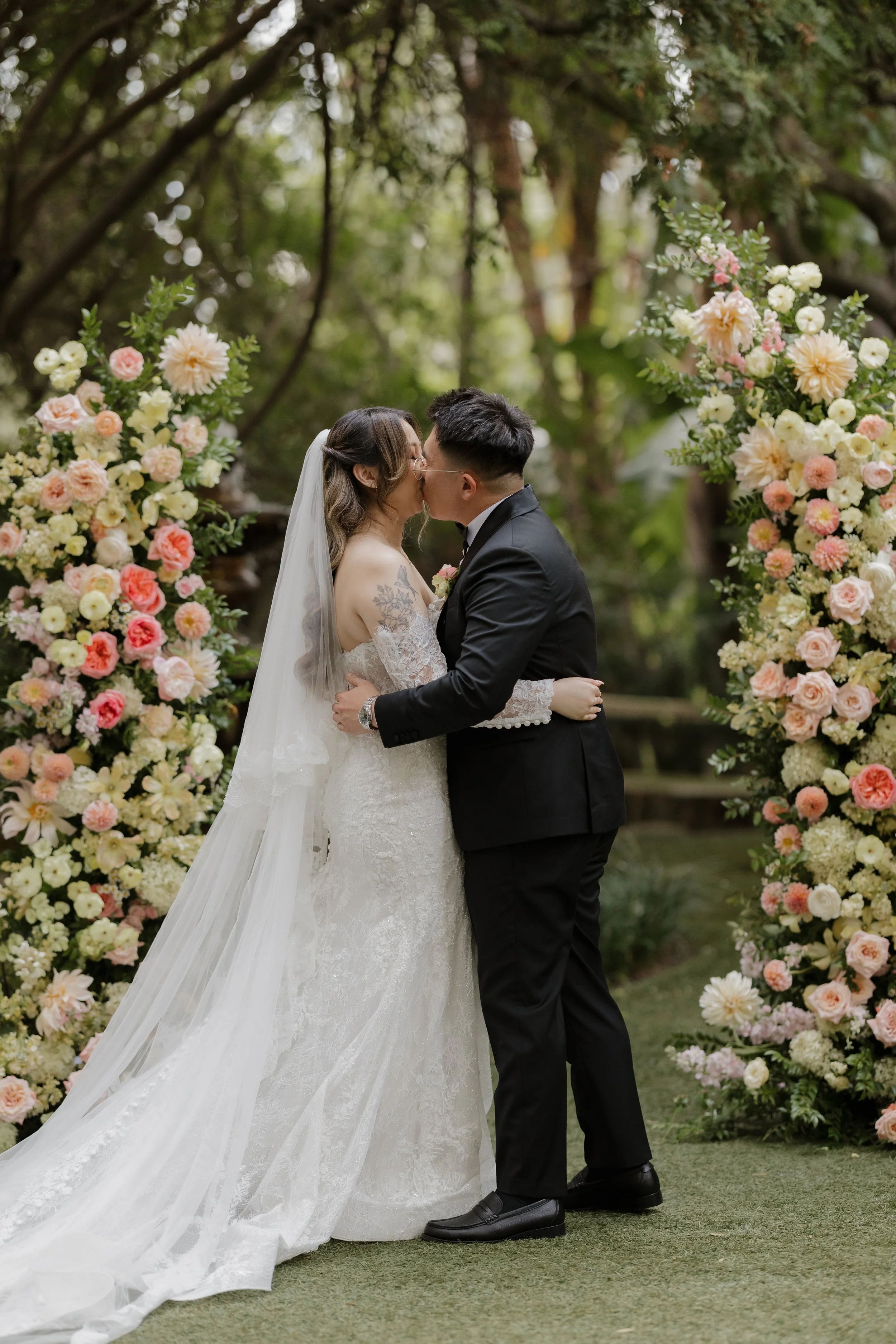Nancy and Ken's first kiss as husband and wife between floral arches at Green Gables
