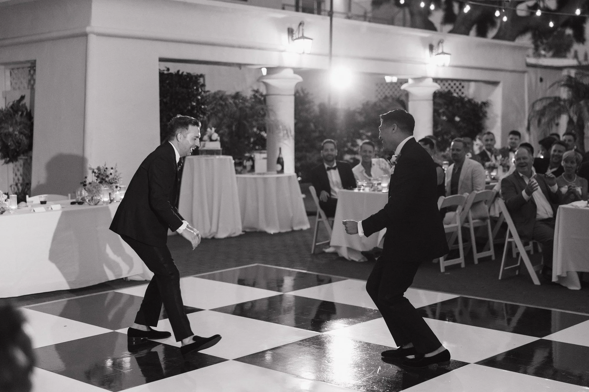Black and white photo of Ryan and Sean dancing playfully on the checkerboard floor