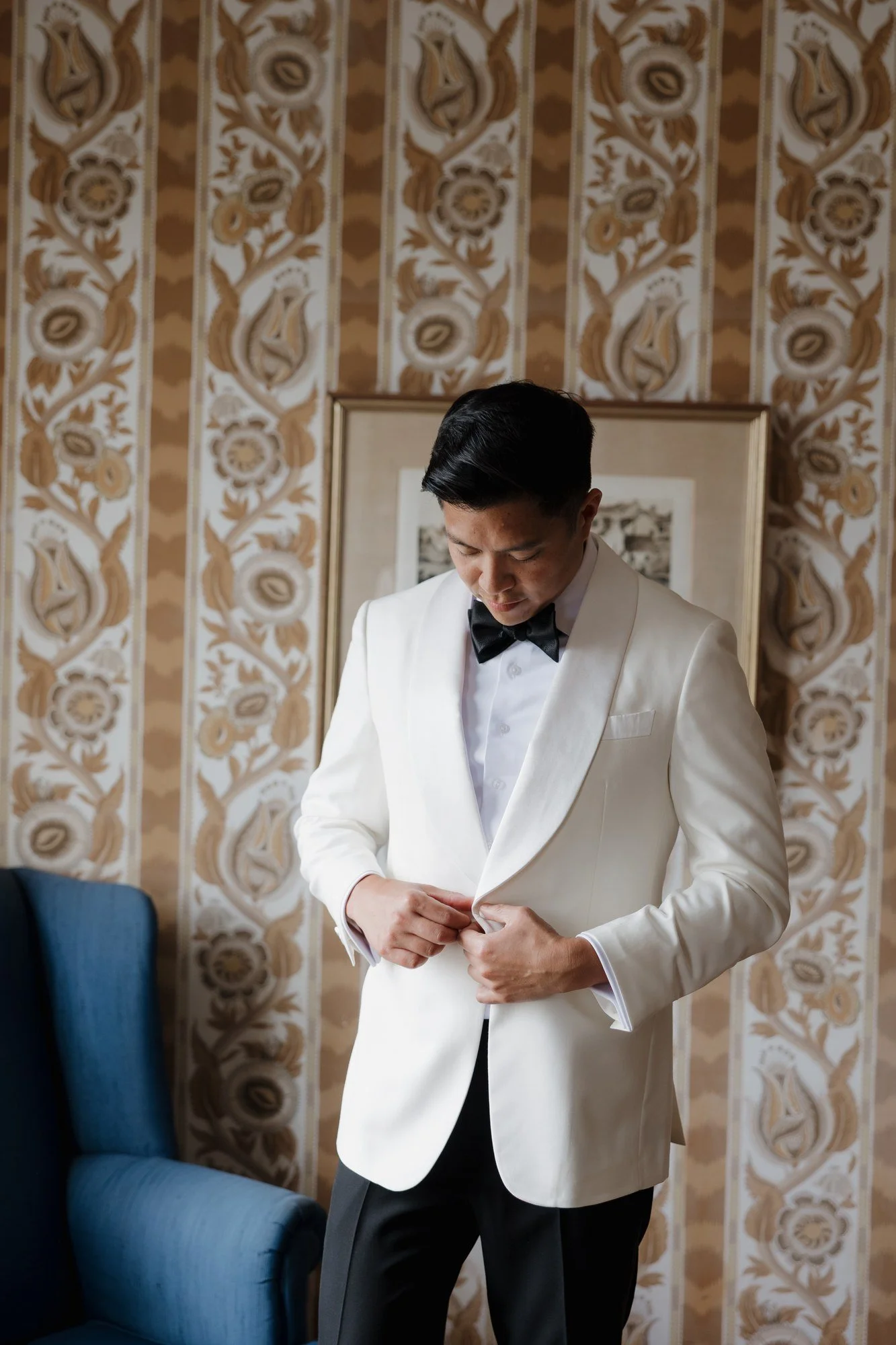 Ryan buttoning his white tuxedo jacket at Darlington House