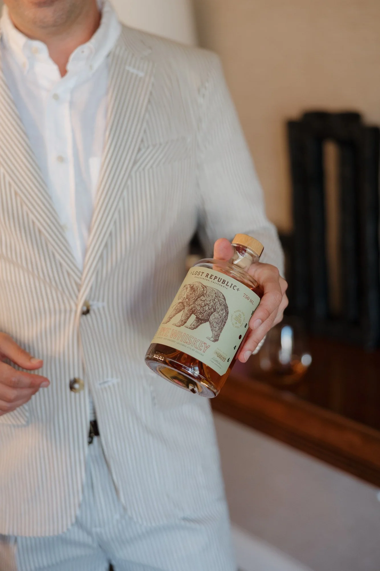 Sean holding a bottle of bourbon while getting ready for the rehearsal dinner at Estancia La Jolla